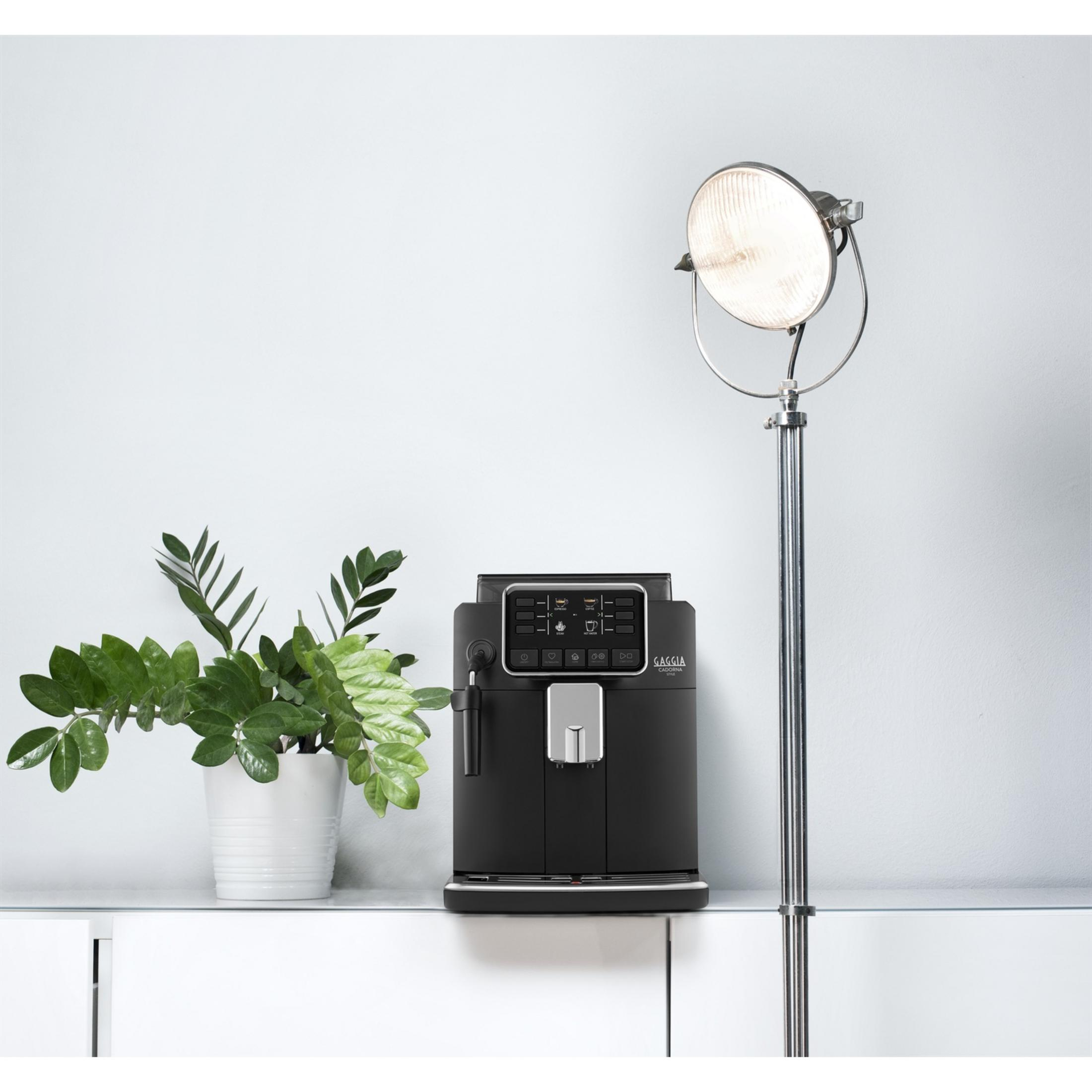 Czarna ekspres do kawy z panelem sterowania, obok rośliny w białej doniczce.