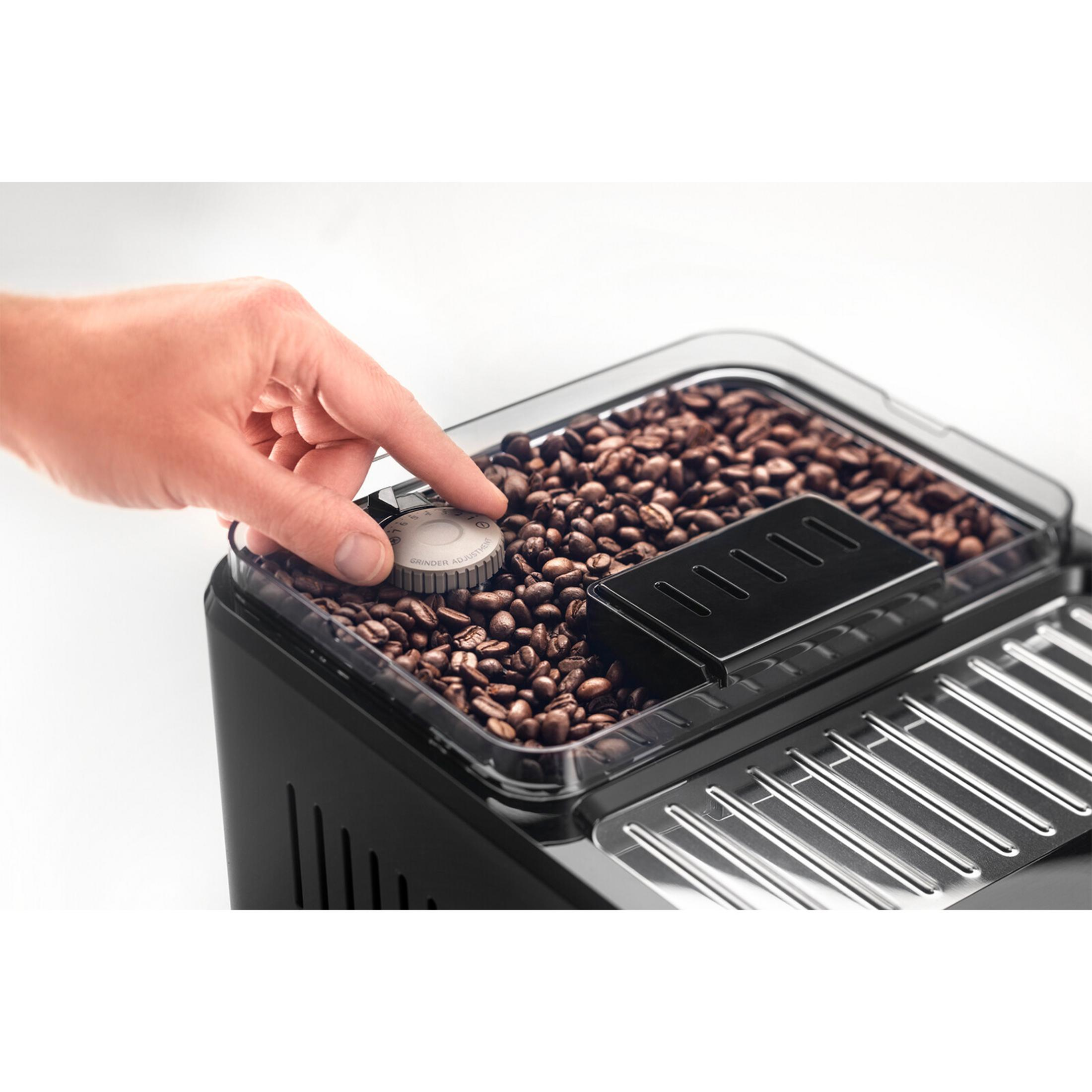 Ręka obraca pokrętło nad ziarnami kawy w pojemniku.