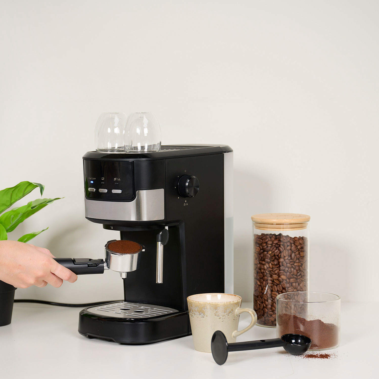 Ręka wkłada uchwyt filtra z mieloną kawą do ekspresu do kawy.