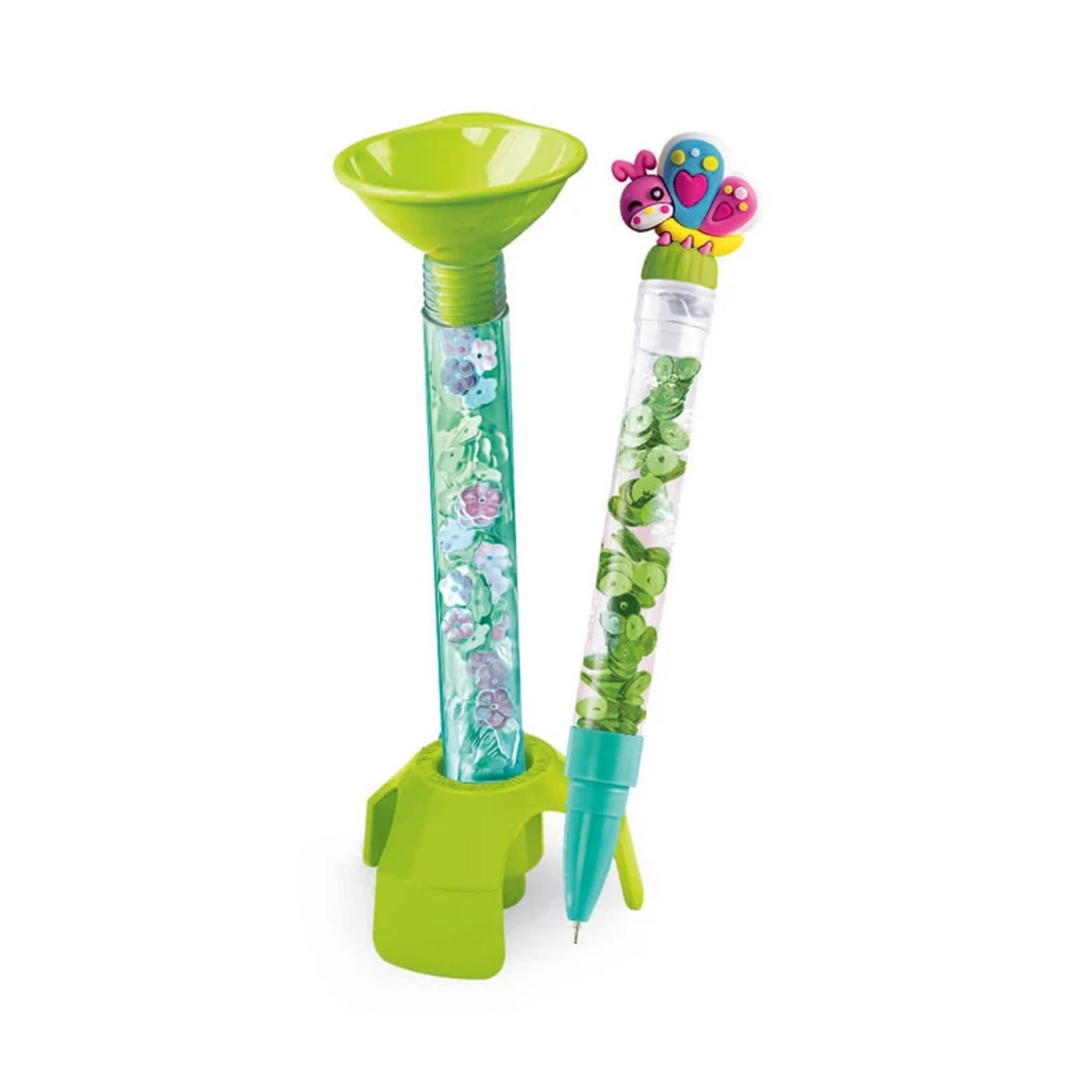 Zielony stojak trzyma dwa długopisy z brokatem i kwiatami.