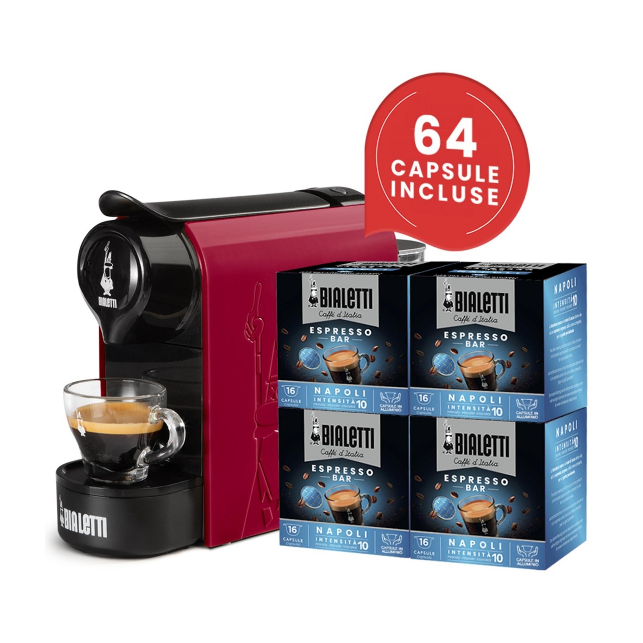 Una macchina per espresso Bialetti rossa con una tazza di caffè e quattro confezioni di capsule.