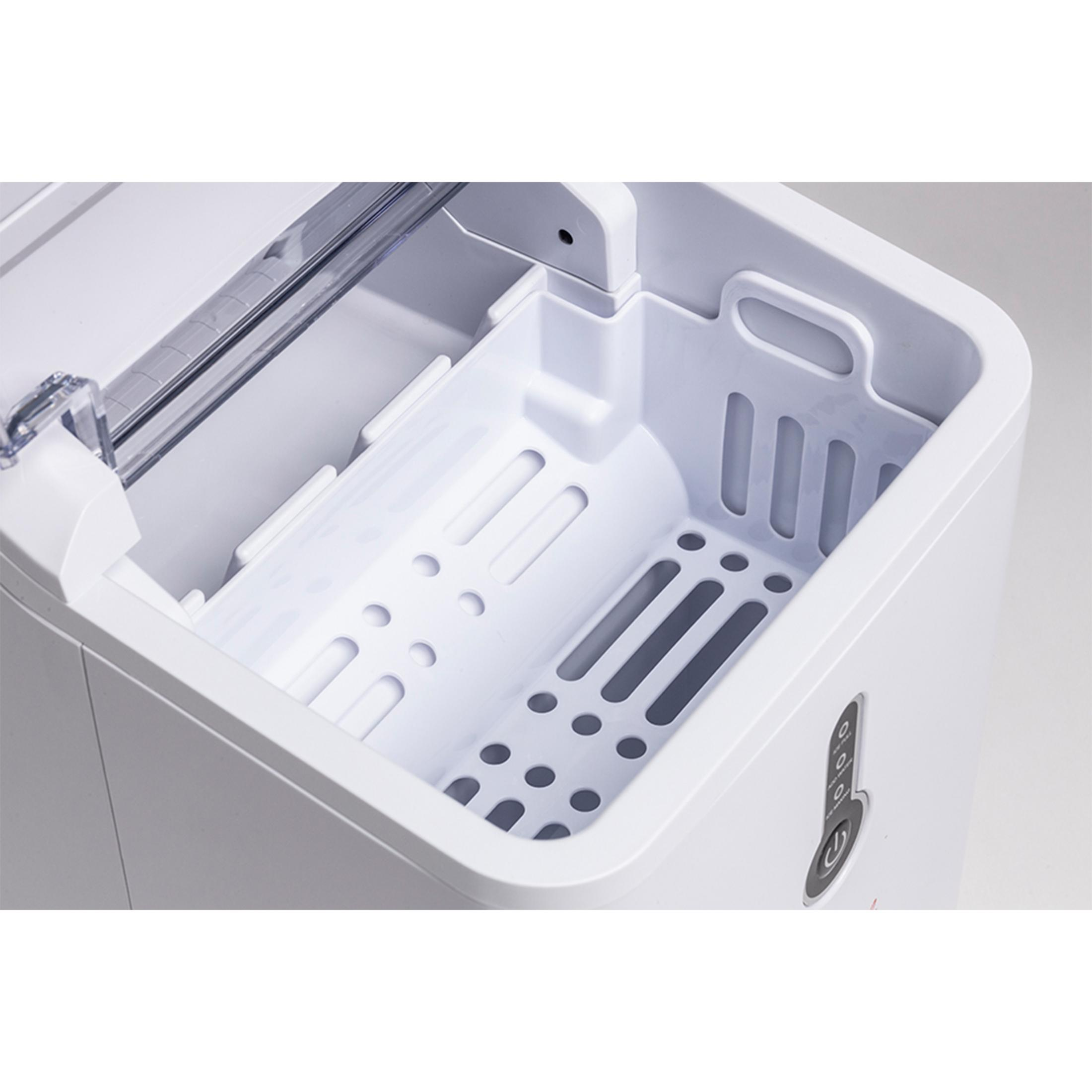 Witte ijsmachine met open vak en witte inzet met gaten.