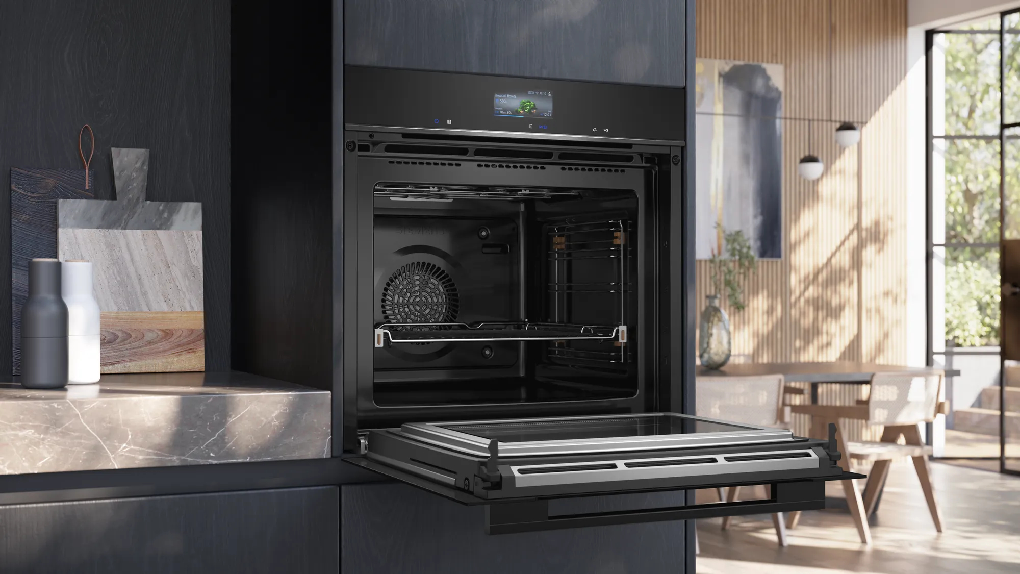 Een moderne zwarte oven met de deur open. Snijplanken en molens ernaast.
