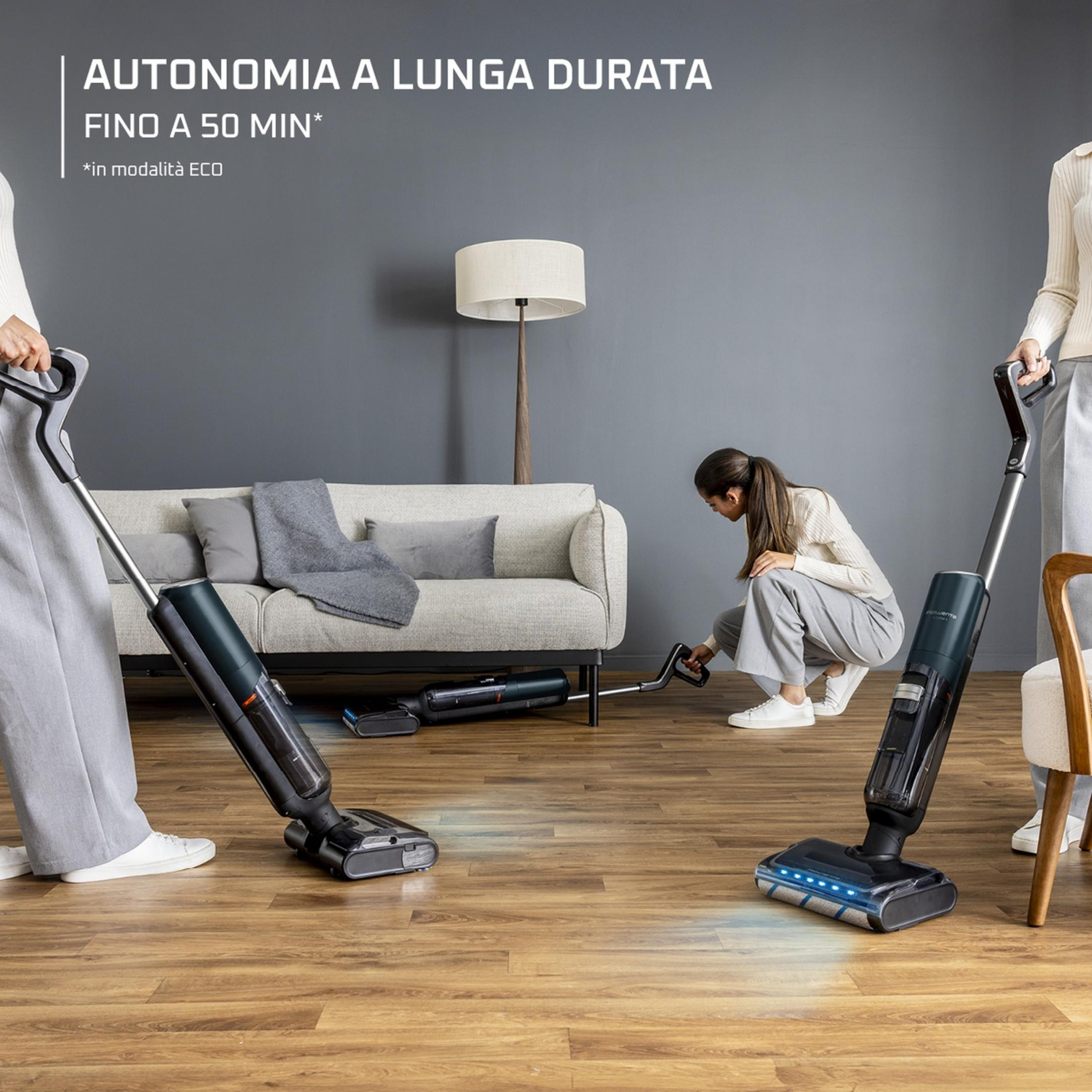 Dos personas limpian un suelo de madera con aspiradoras inalámbricas en una sala de estar moderna.