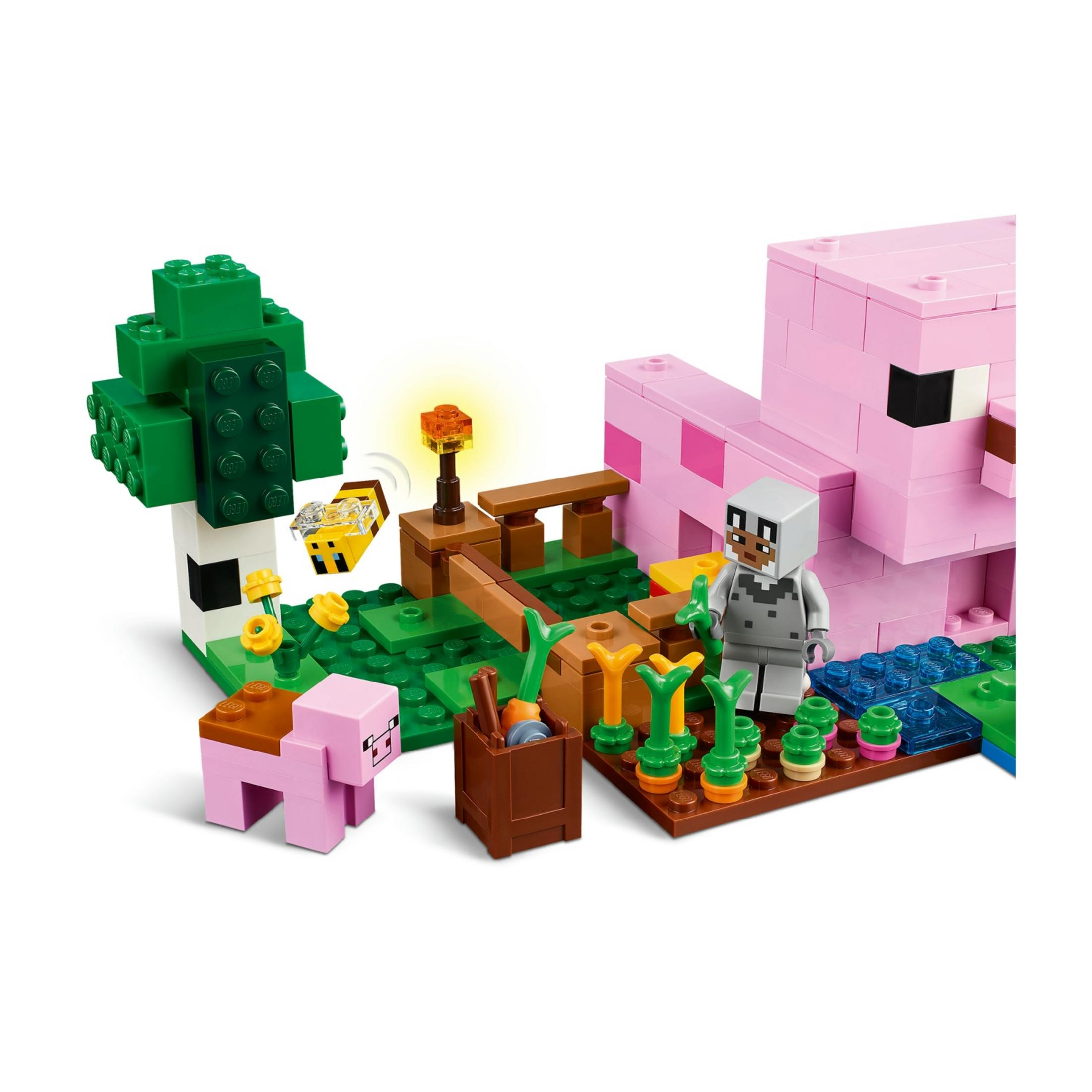 Scena Lego z różową świnią, postacią, drzewem, ulem i grządką z marchewkami.