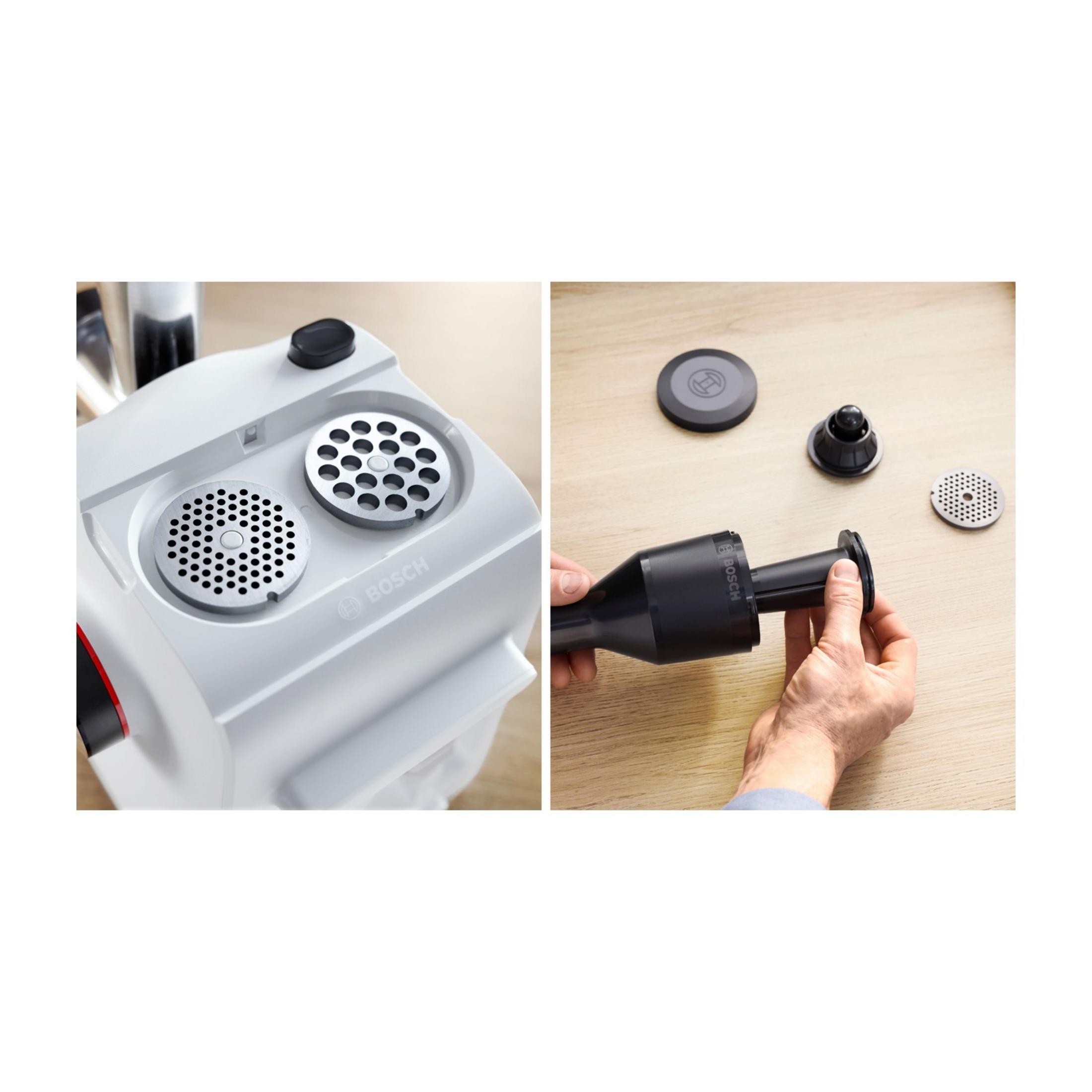 Zbliżenie białej maszynki do mielenia mięsa z dwiema tarczami i osobą trzymającą czarny dodatek.