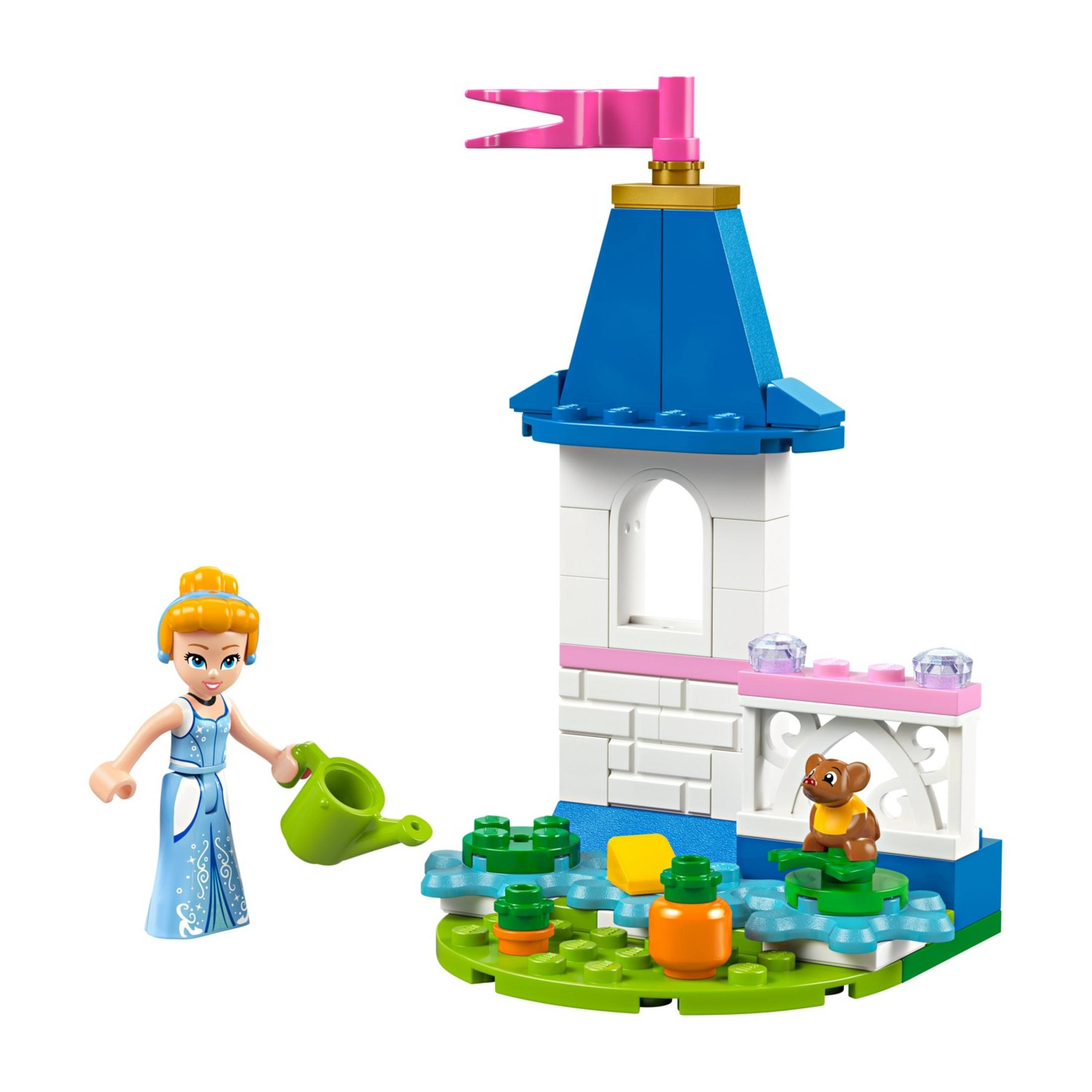 Dziewczynka Lego w niebieskiej sukience podlewa rośliny obok wieży z misiem.