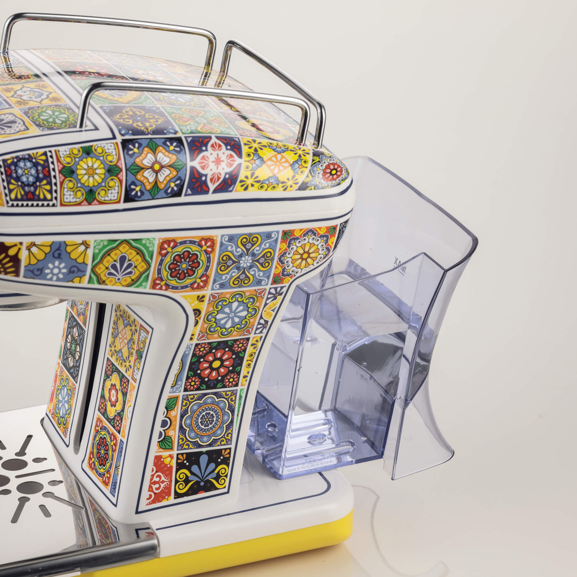 Ekspres do kawy zdobiony kolorowymi kafelkami i srebrnymi uchwytami.