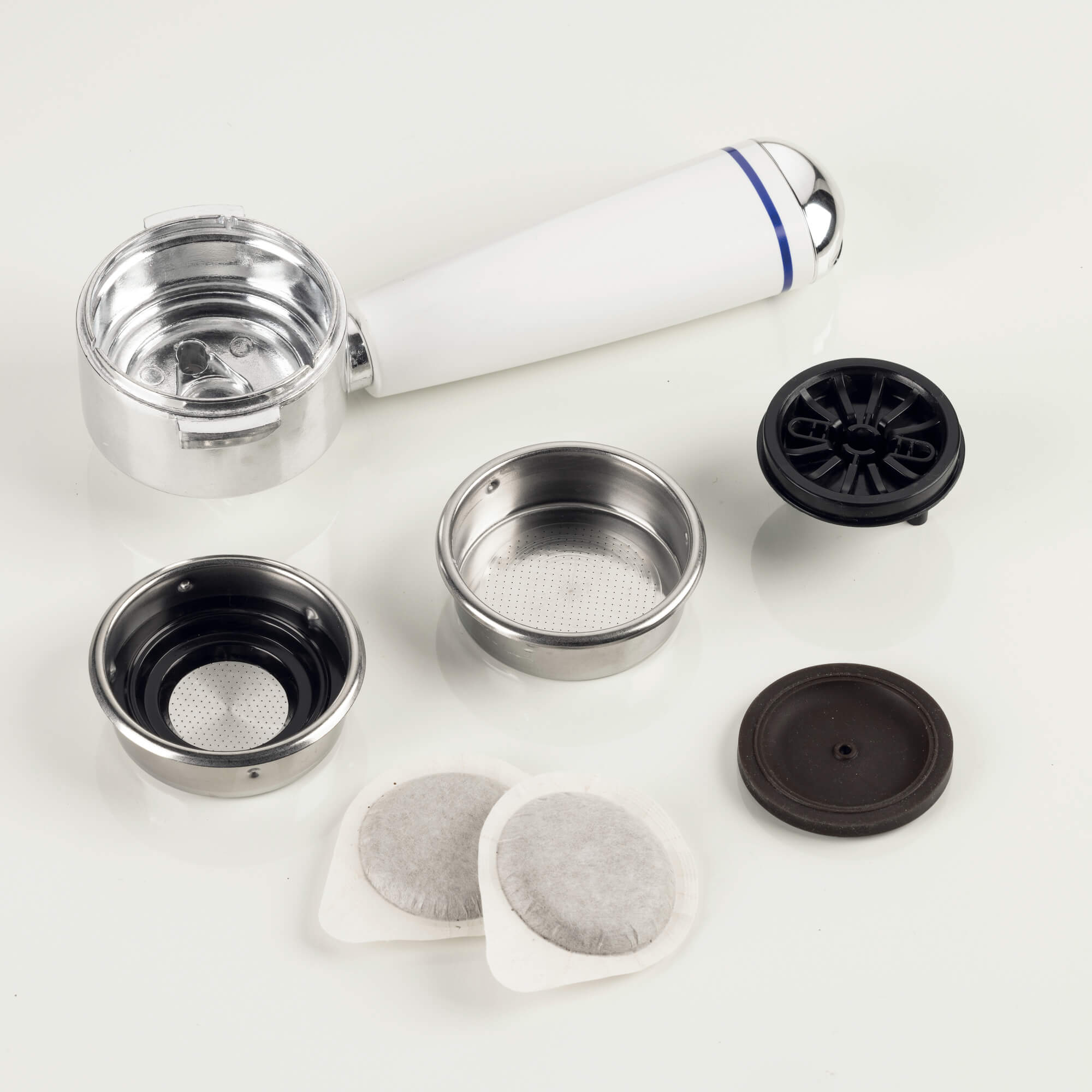 Uchwyt filtra ekspresu do kawy z sitkami i kapsułkami kawy na białym tle.