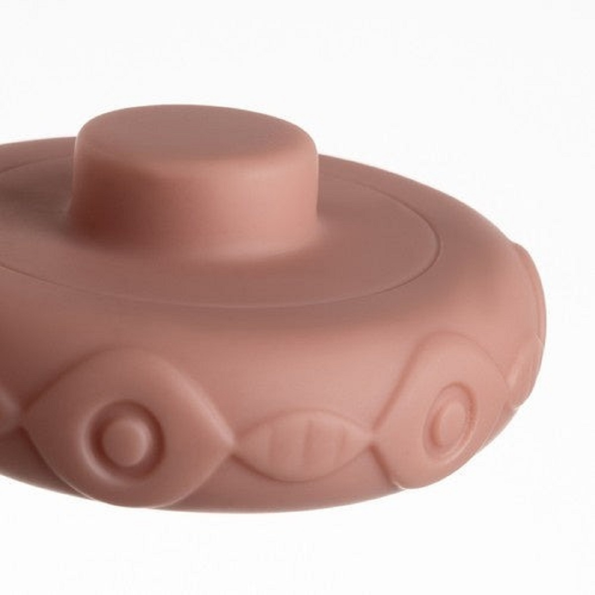 Un juguete de goma rosa con forma de hongo y patrones circulares.