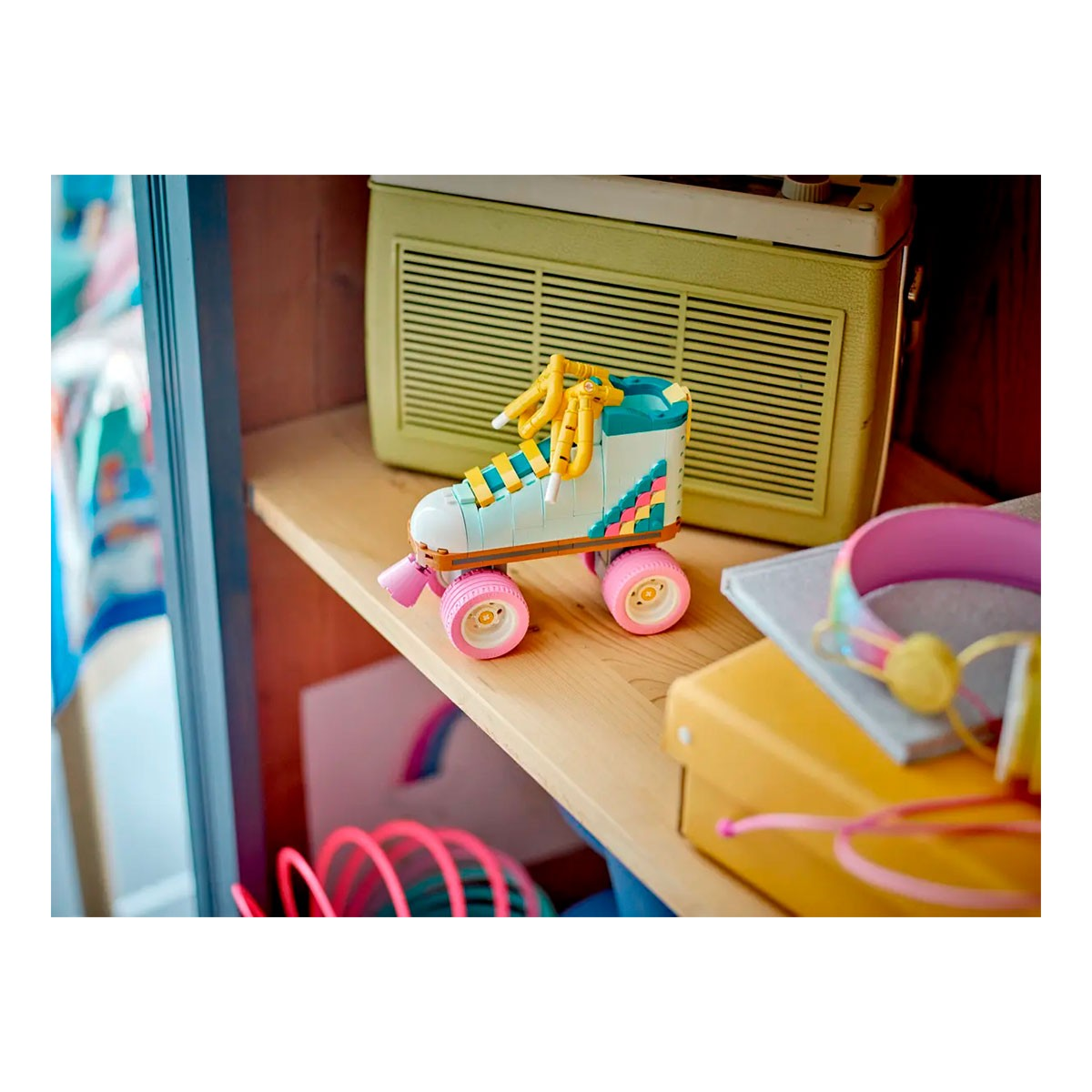 Zabawkowa rolka z żółtymi sznurowadłami stoi na półce obok radia.