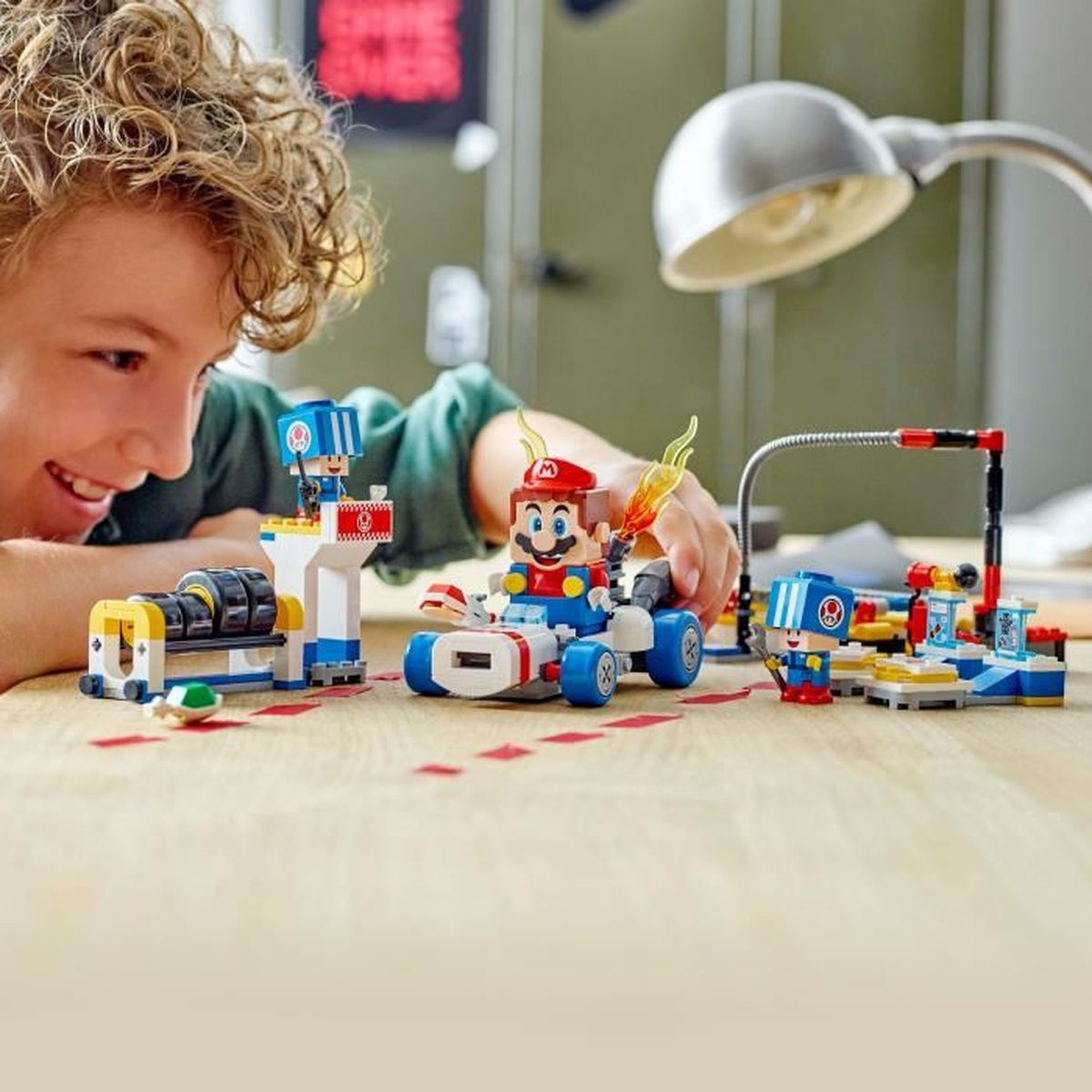 Bir çocuk go-kartta Lego Mario ve Luigi figürleriyle oynuyor.