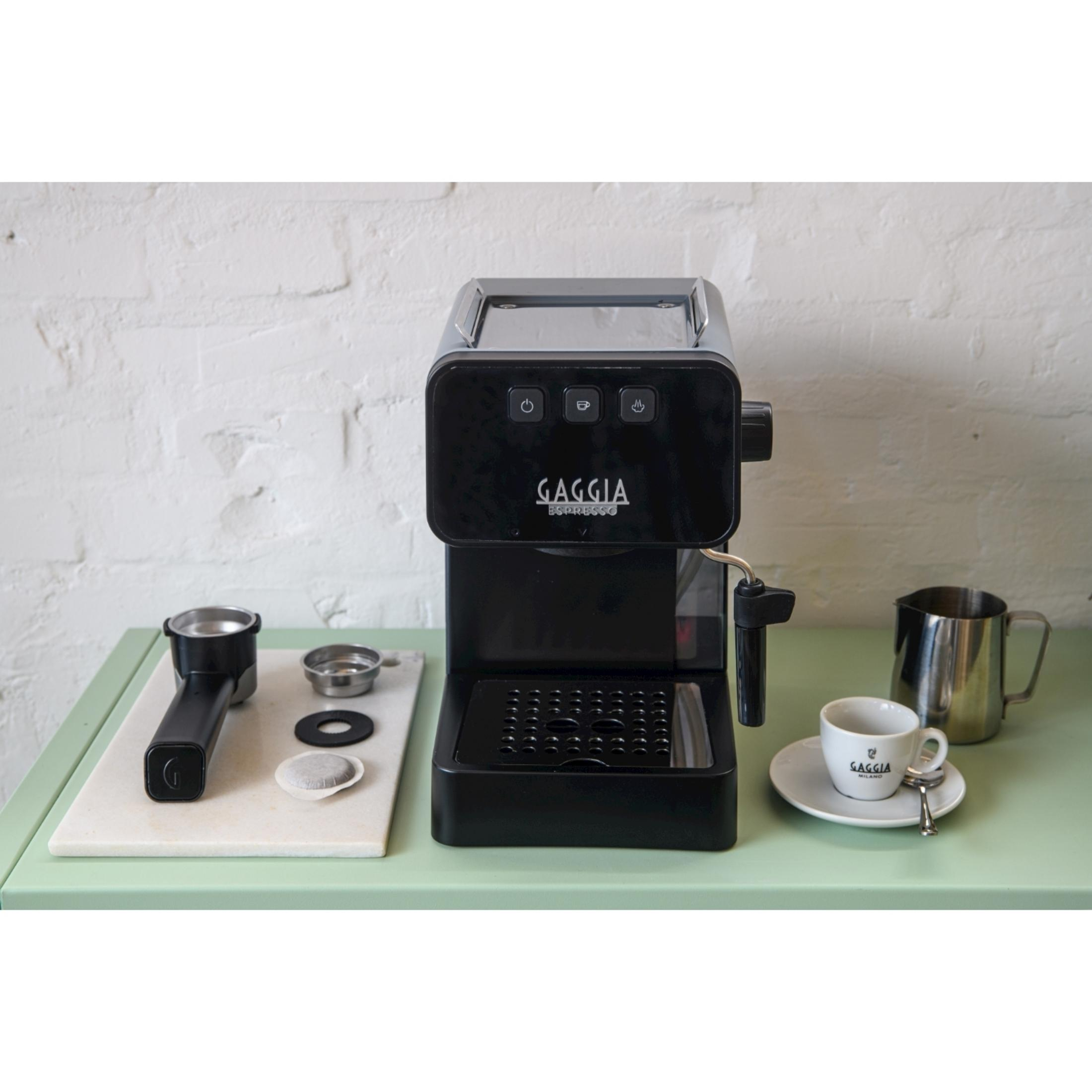 Czarna ekspres do kawy Gaggia z akcesoriami, filiżanką i dzbankiem na mleko.