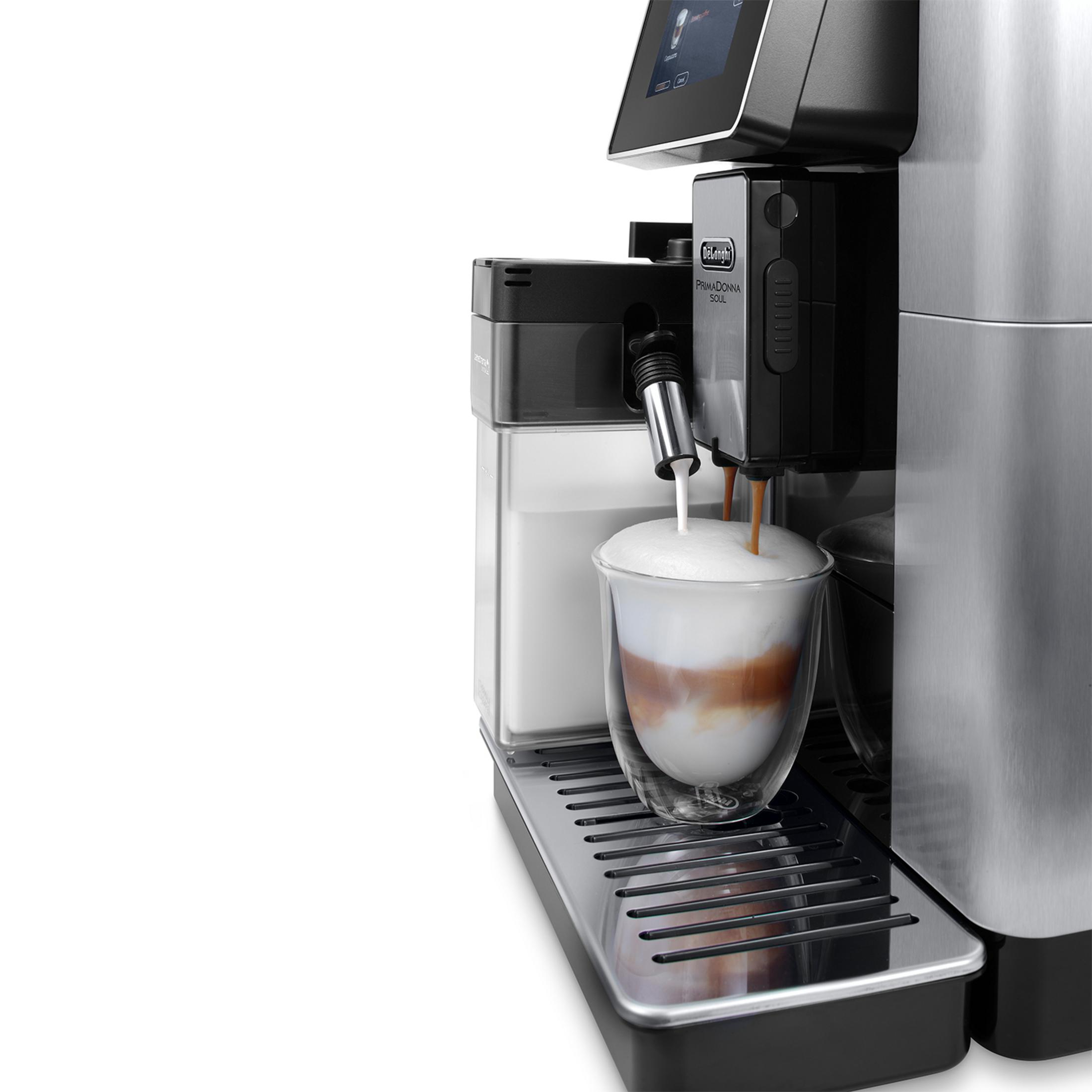 Eine Kaffeemaschine brüht ein Getränk mit Milchschaum in ein Glas.