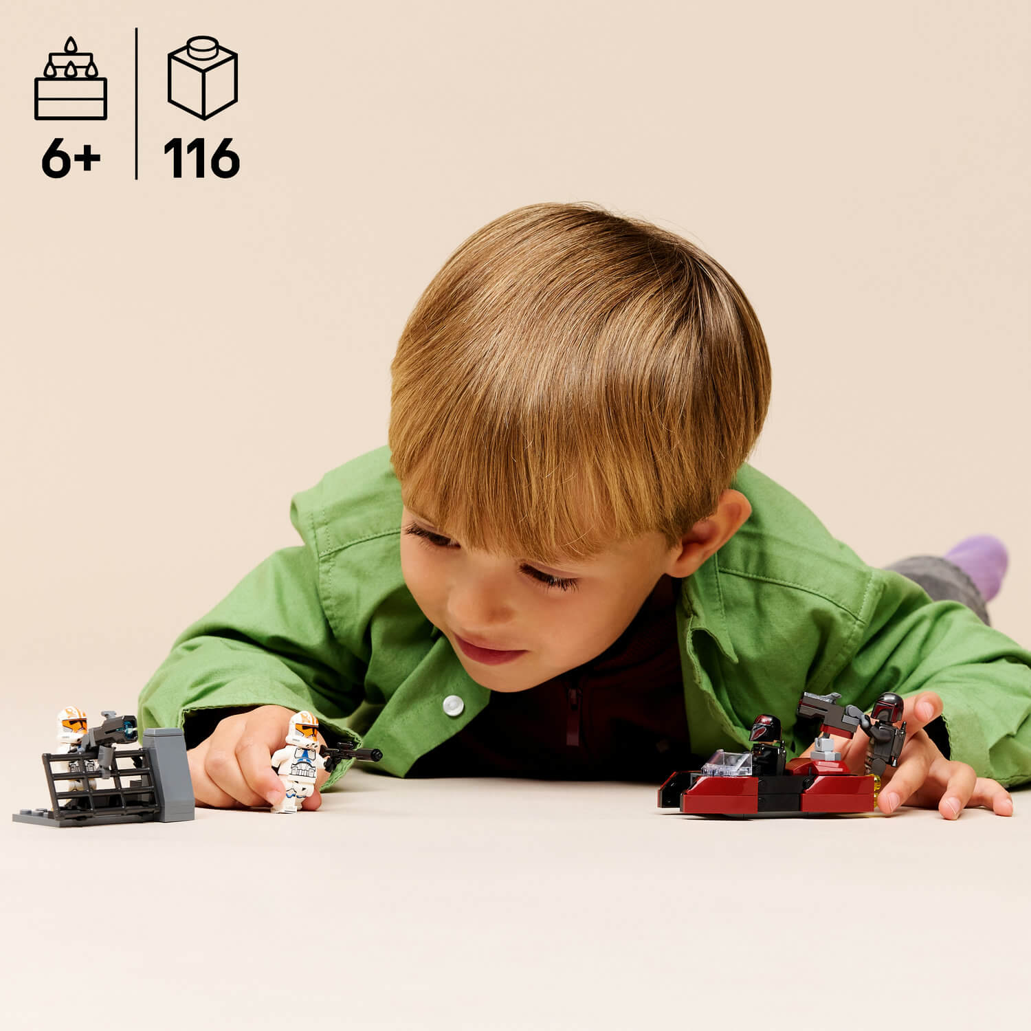 Un niño juega con figuras y vehículos de Lego sobre un fondo beige claro.