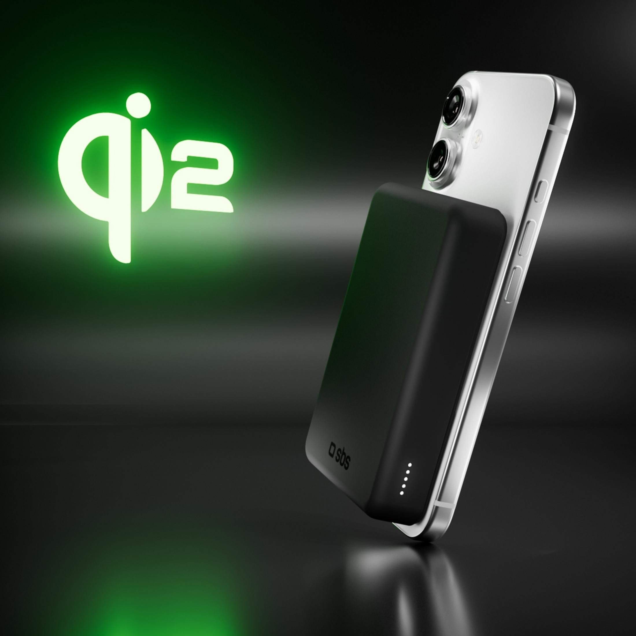 Un caricatore Qi nero su uno smartphone argentato con sfondo verde.