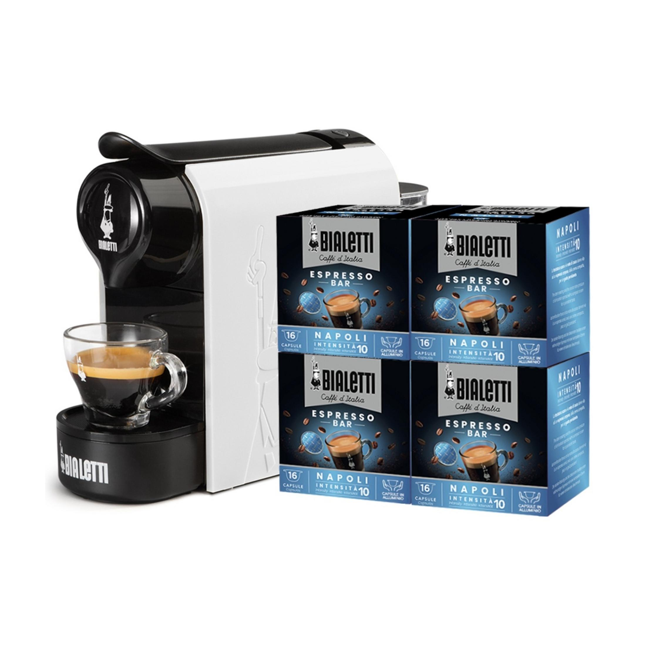 Una macchina da caffè bianca e nera con una tazza di espresso e quattro scatole di capsule.