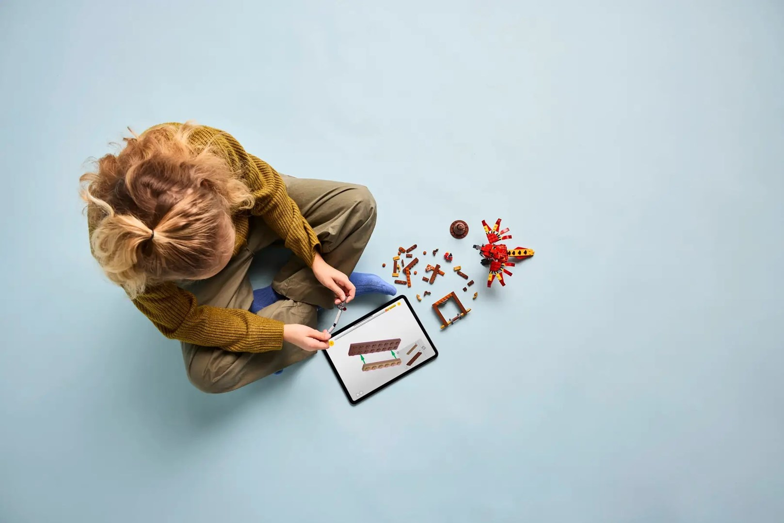 Dziecko buduje z klocków, patrzy na ekran tabletu.