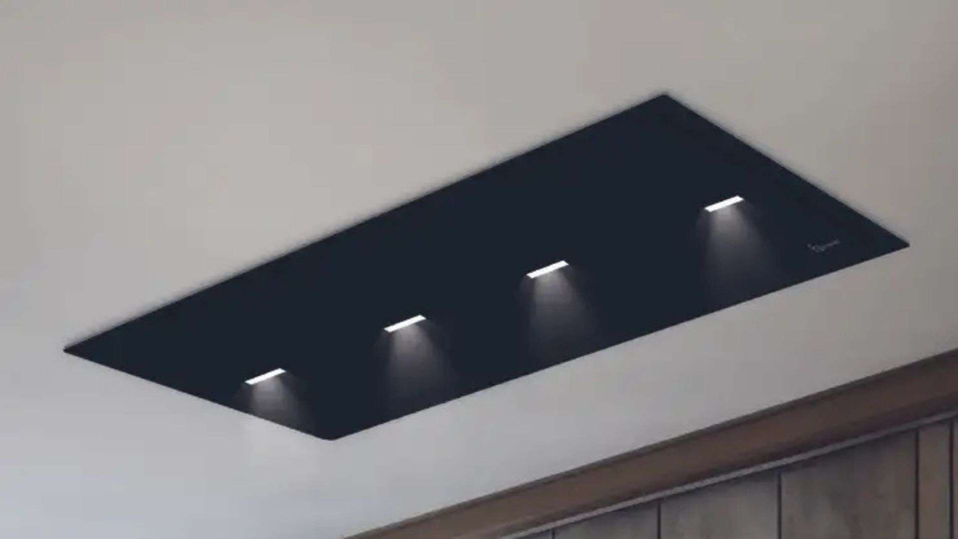 Pannello da soffitto scuro con quattro luci integrate in una stanza.
