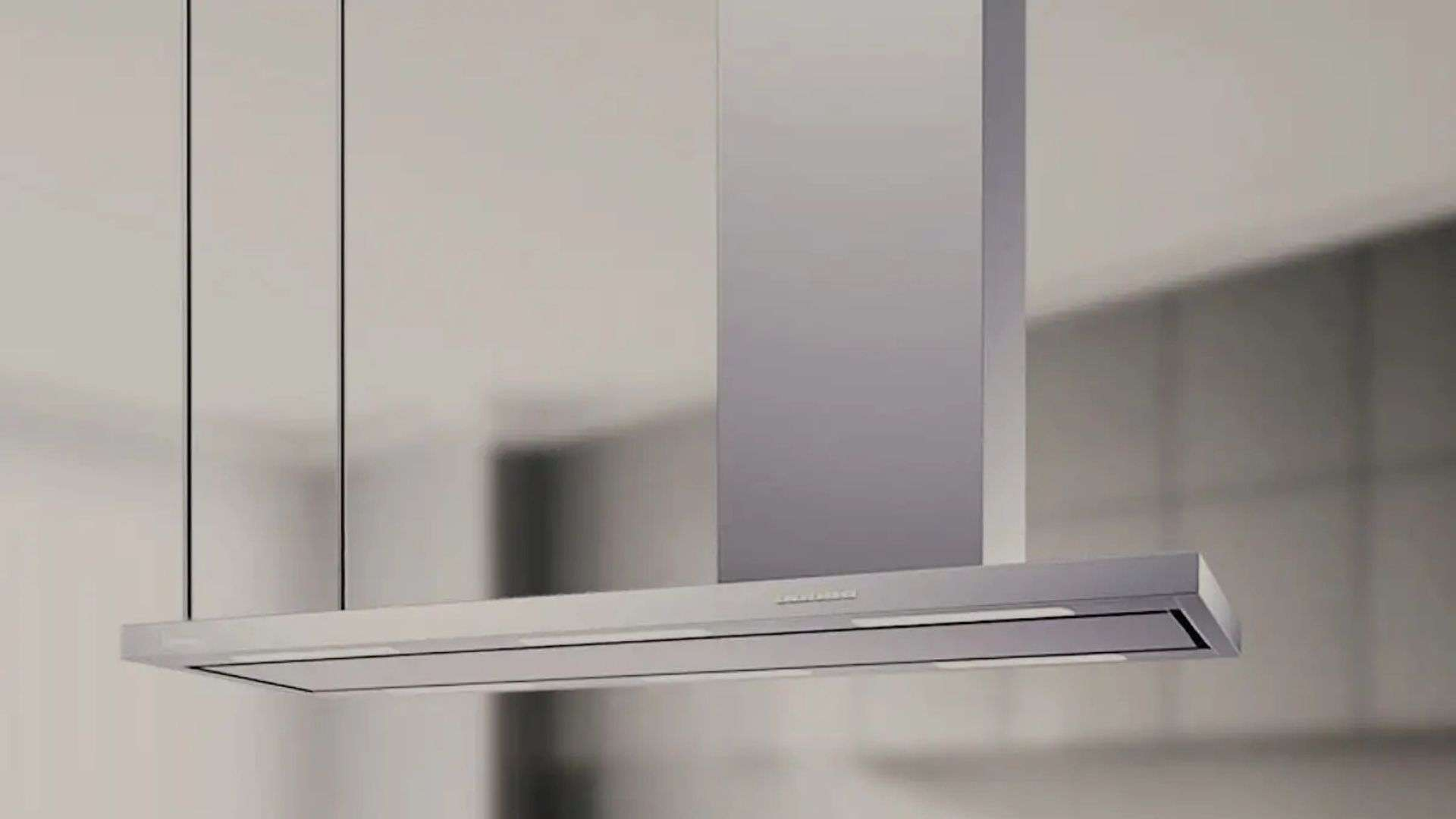 Una cappa da cucina moderna argentata con illuminazione pende sopra un piano di lavoro.
