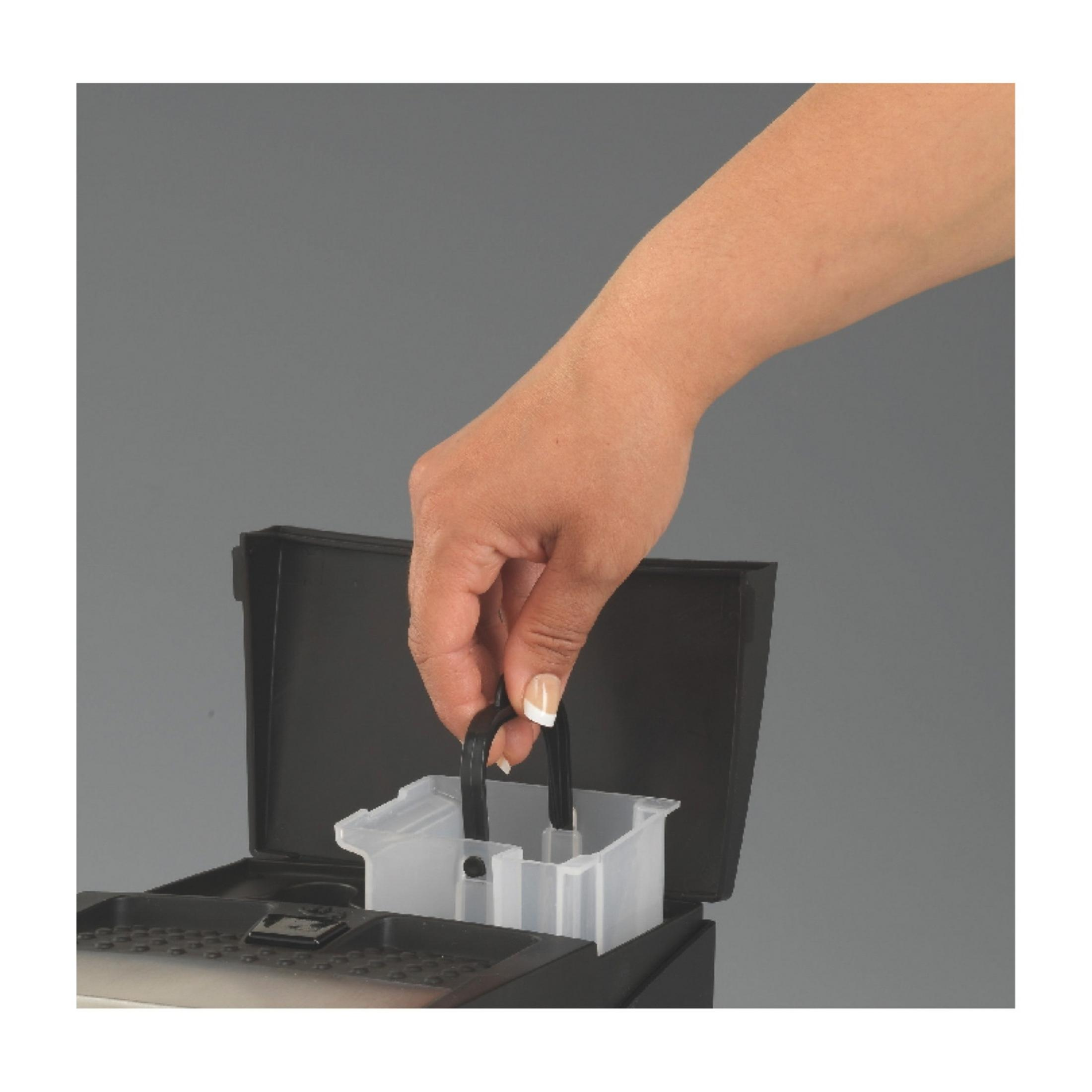 Ręka trzyma dwa czarne uchwyty przezroczystego pojemnika.