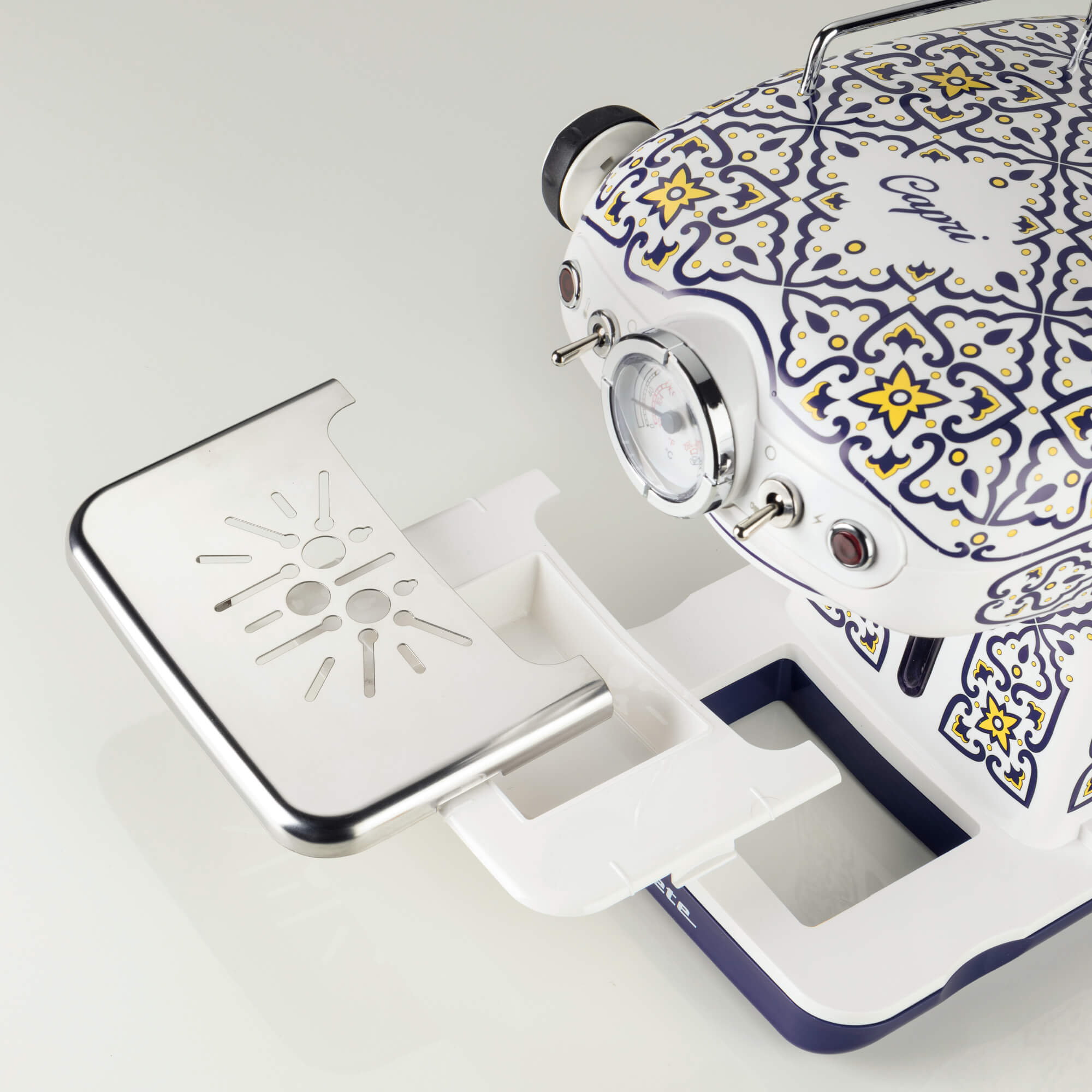 Biała maszyna do kawy z niebiesko-żółtymi wzorami i metalową tacką ociekową.