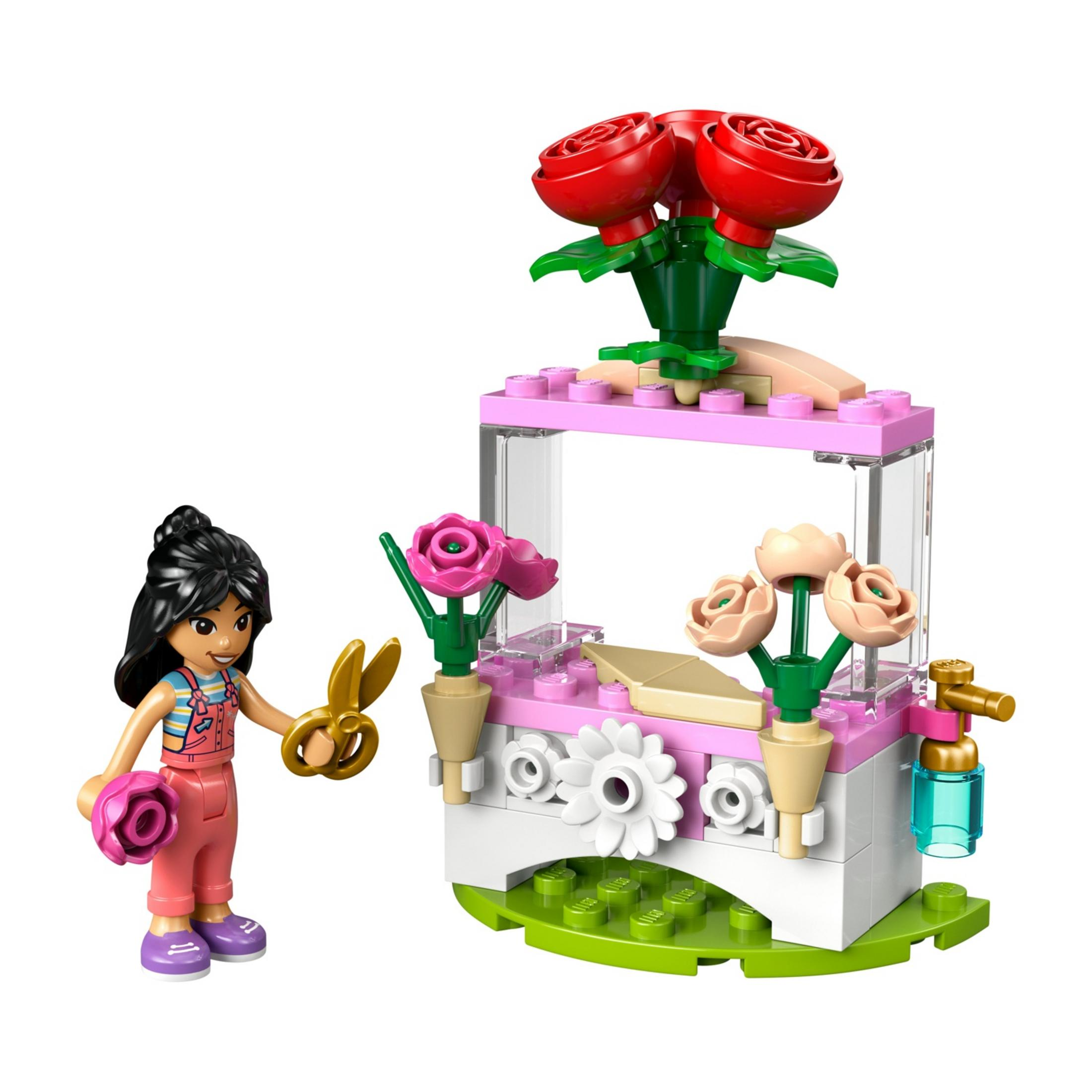 Una figura de Lego con tijeras y una flor junto a un puesto de flores con rosas.