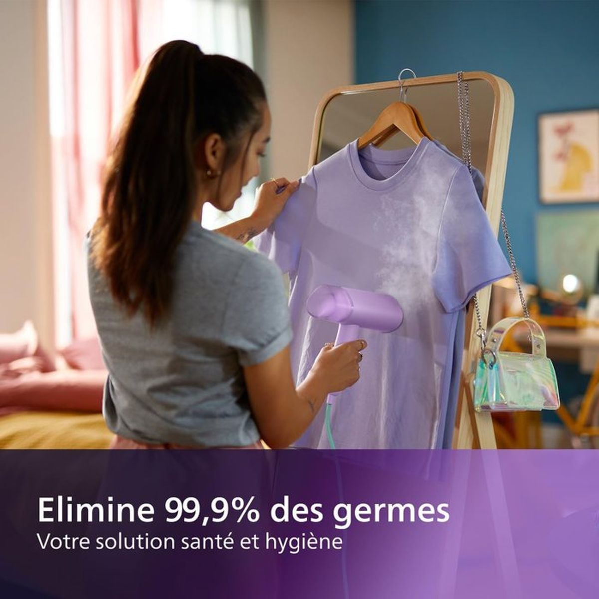 Kobieta prasuje fioletową koszulkę parownicą ręczną w sypialni.