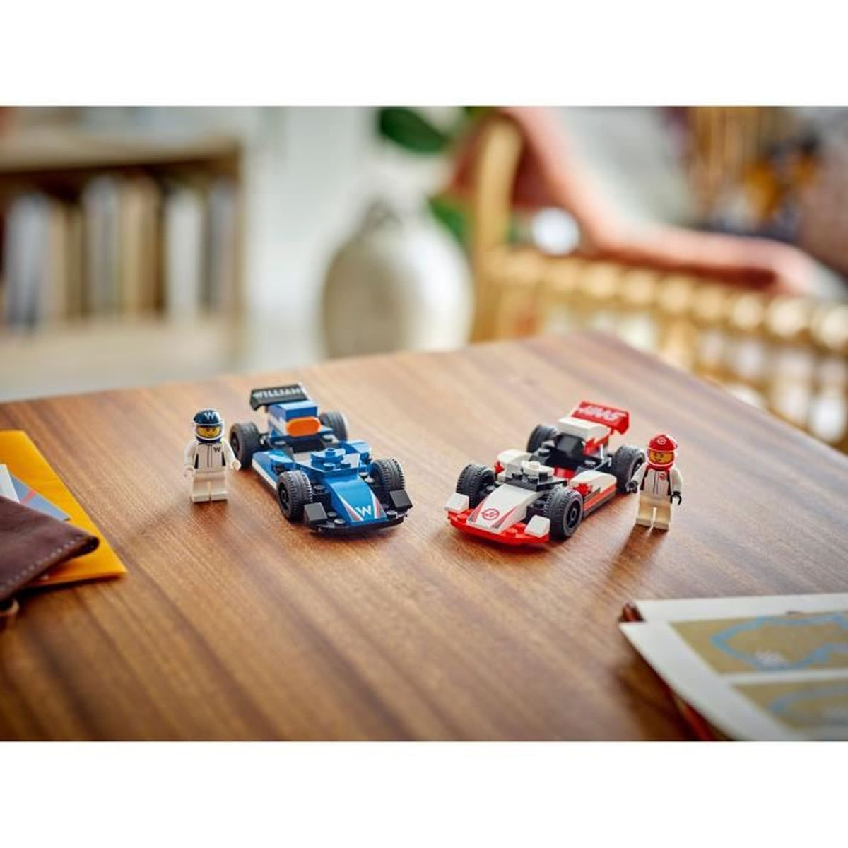 Dos coches de Fórmula 1 de Lego, uno azul y otro rojo/blanco, con pilotos en mesa de madera.