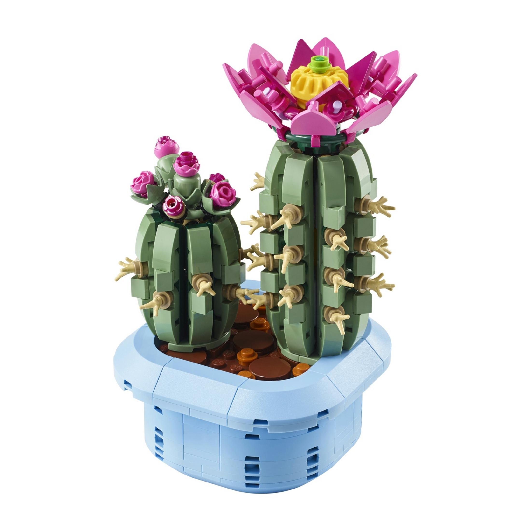 Dos cactus verdes de Lego con flores rosas y piedras marrones en una maceta azul.