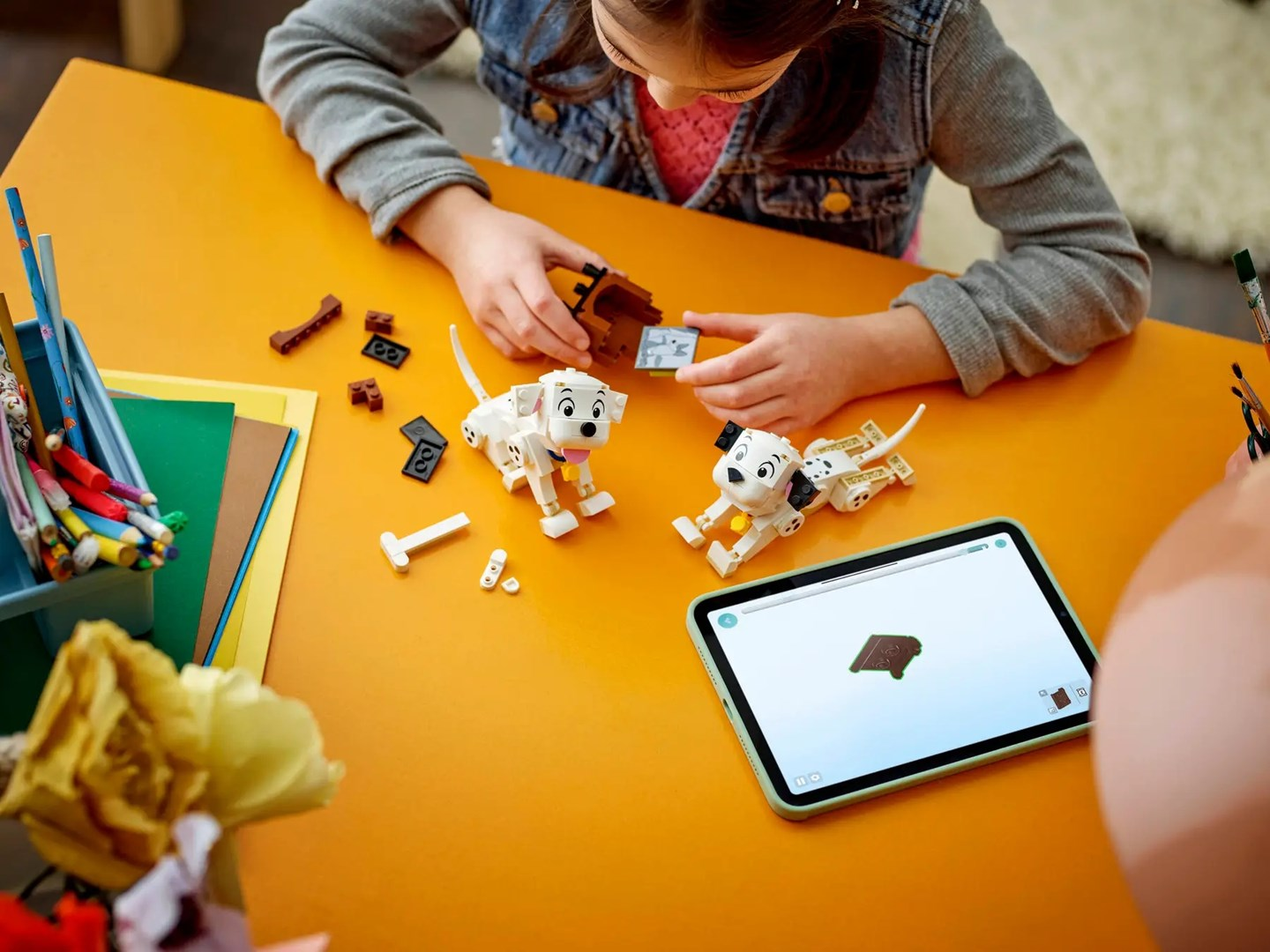Çocuklar Lego dalmaçyalılar inşa ediyor. Bir tablet talimatları gösteriyor.