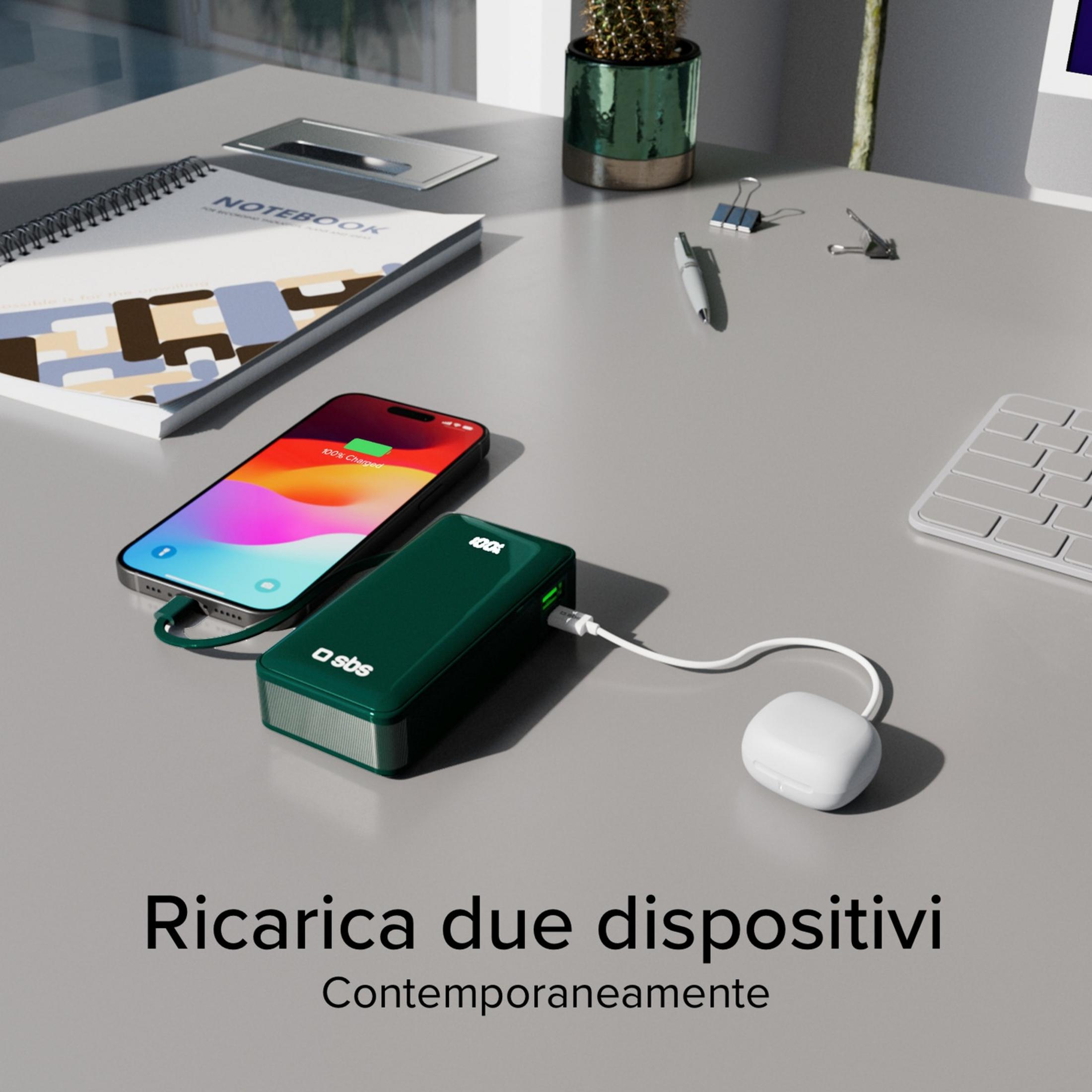 Un power bank verde carica uno smartphone e auricolari bianchi su una scrivania.