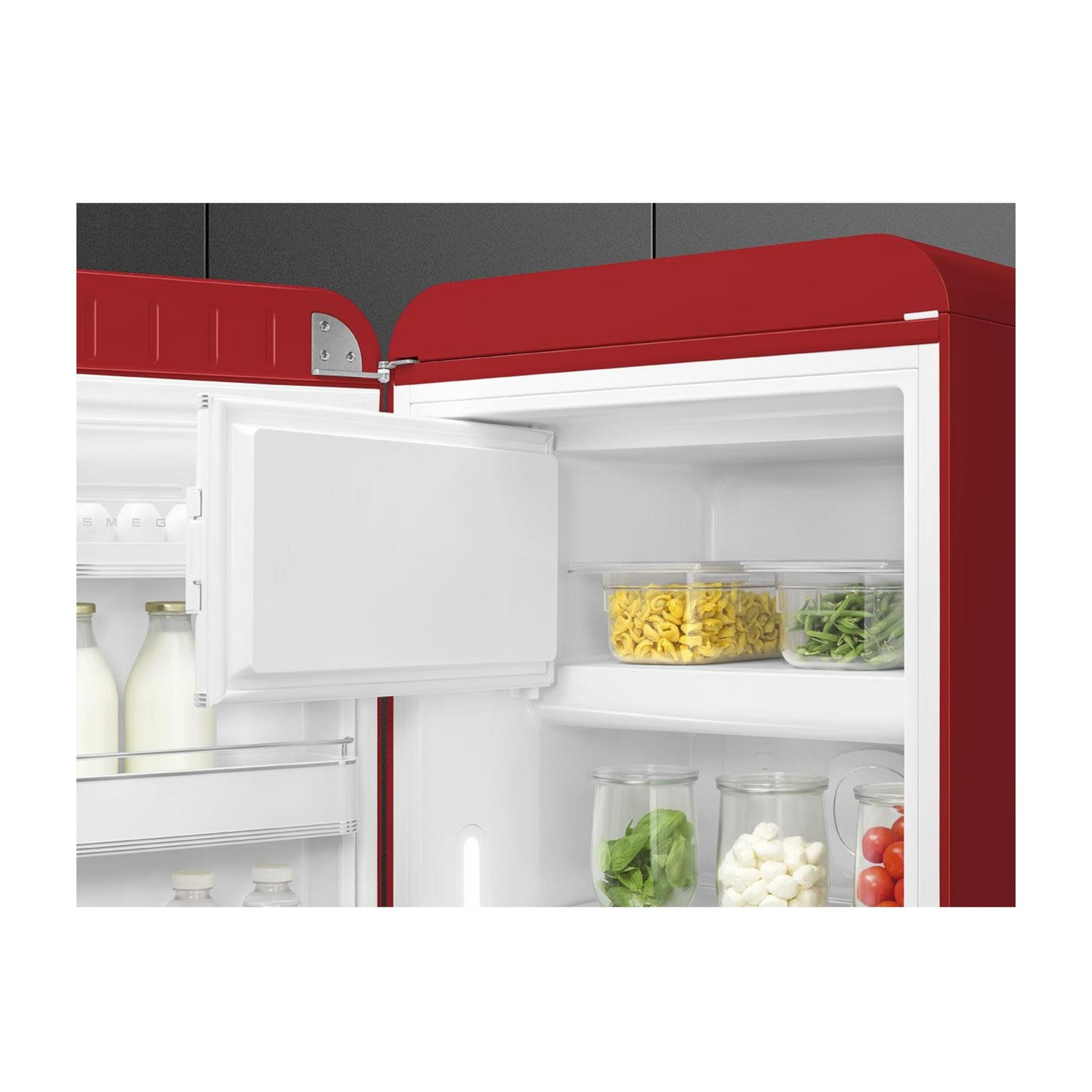 Roter Kühlschrank mit offenem Fach und Lebensmitteln wie Nudeln, Bohnen, Spinat, Käse und Tomaten.