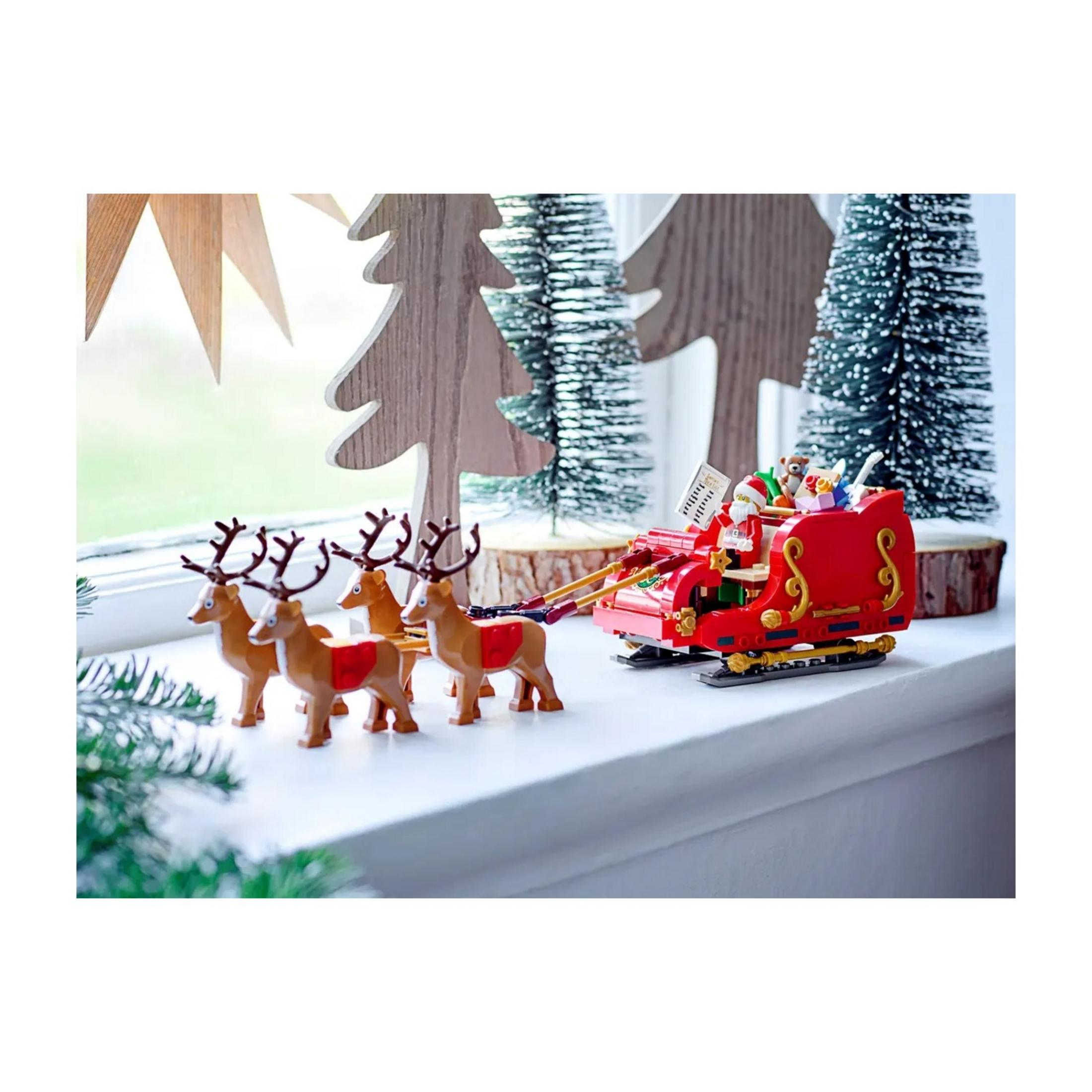 Ein Spielzeug-Schlitten mit Weihnachtsmann und Rentieren auf einem Fensterbrett.