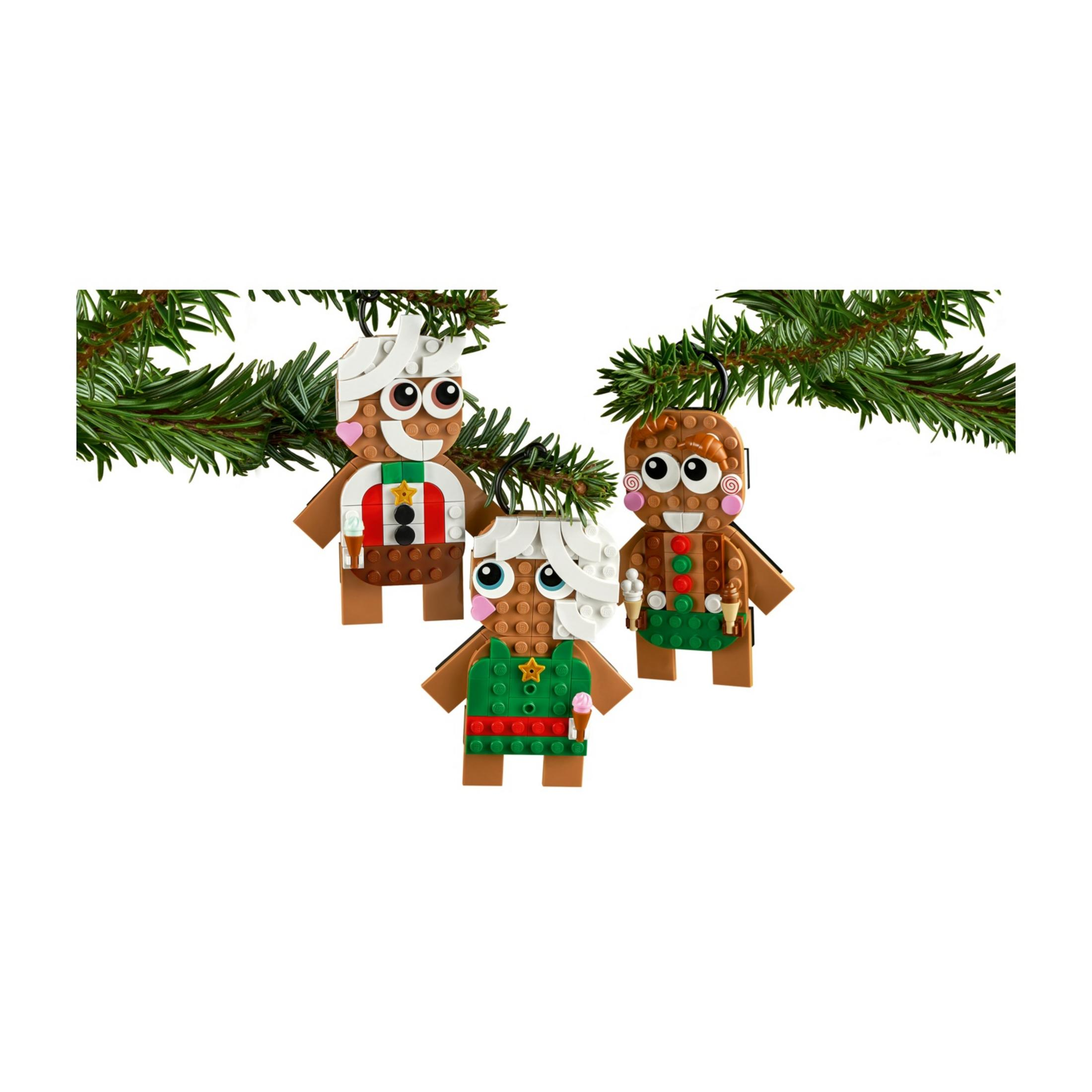 Drei Lebkuchenmännchen aus LEGO-Steinen hängen an einem Tannenzweig.