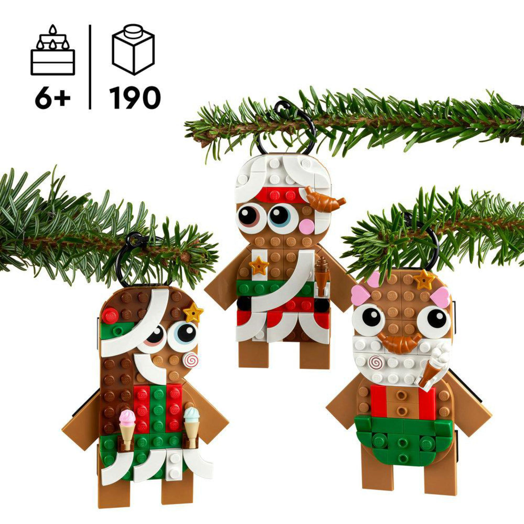 Drei Lego-Figuren im Weihnachts-Design hängen an einem Tannenbaumzweig.