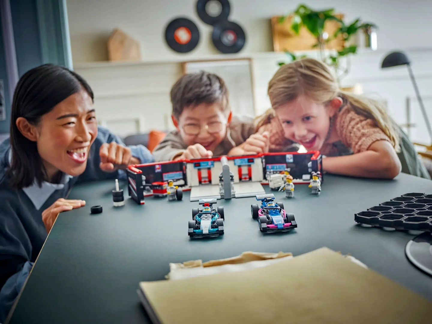 Trzy osoby patrzą na zestaw zabawek samochodzików wyścigowych.