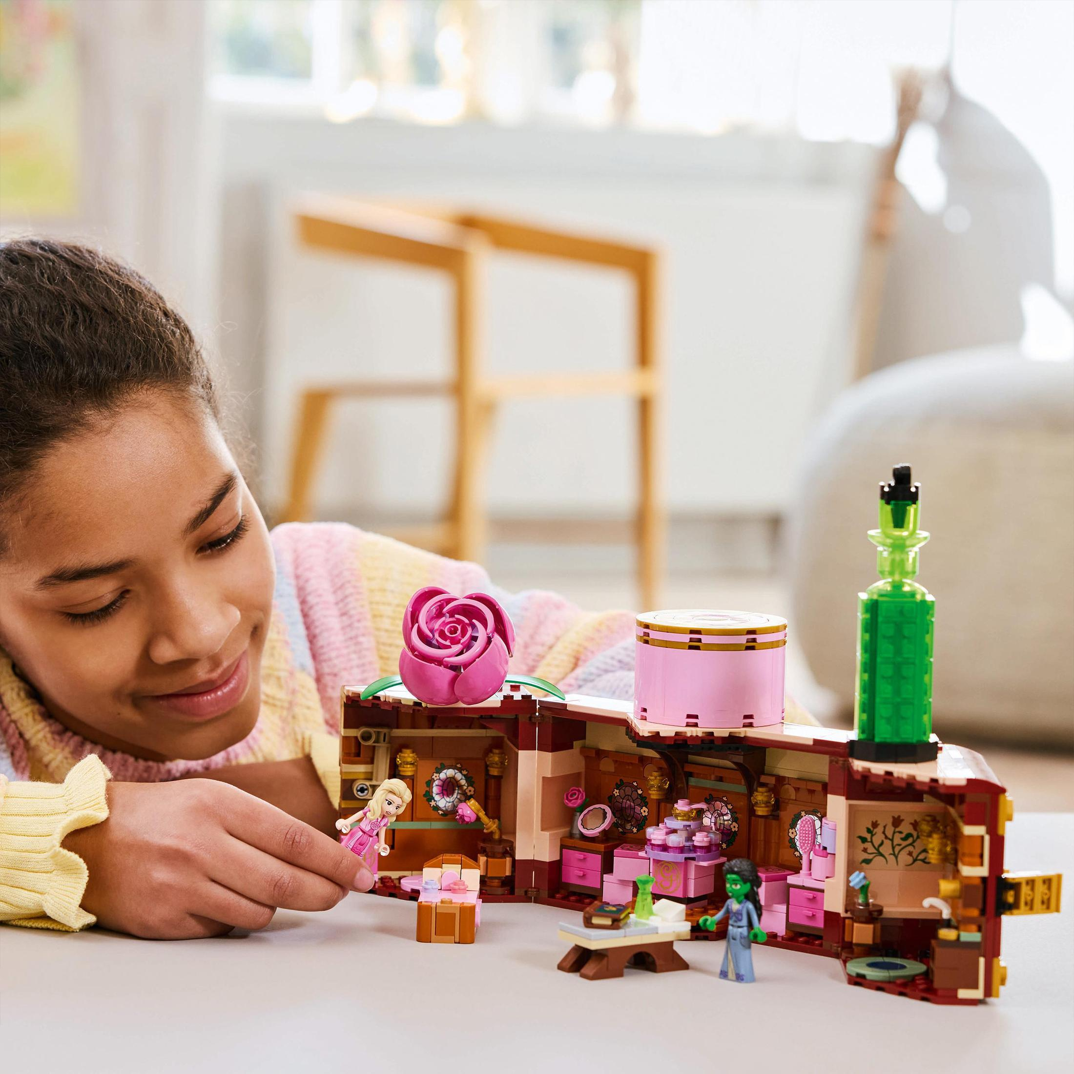 Dziewczynka bawi się zamkiem z klocków Lego z postaciami i różą.