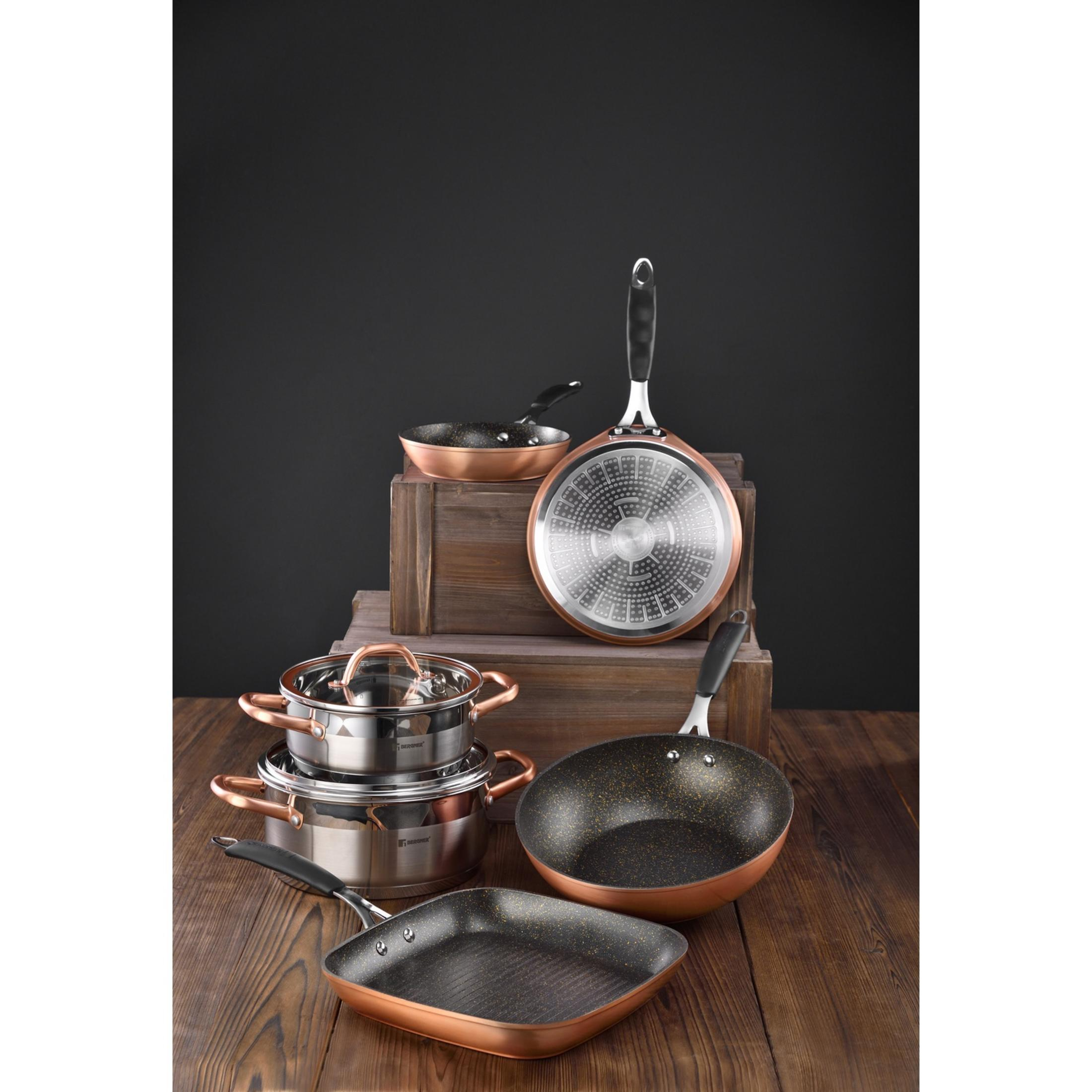 Juegos de utensilios de cocina de metal color cobre sobre superficie de madera.