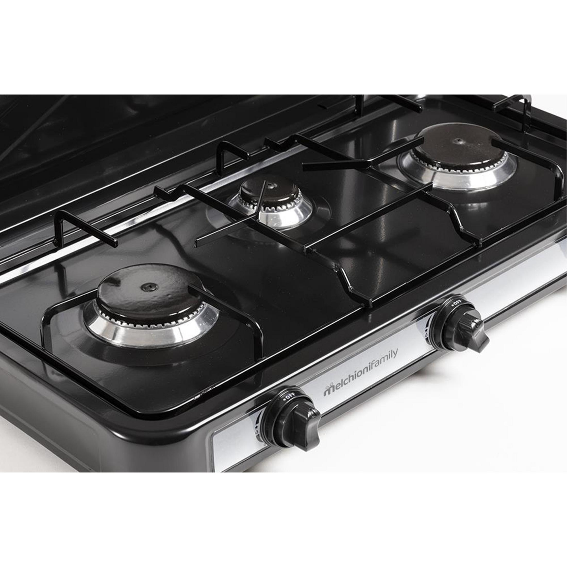 Cocina de gas negra con tres quemadores y detalles plateados. Vista cercana.