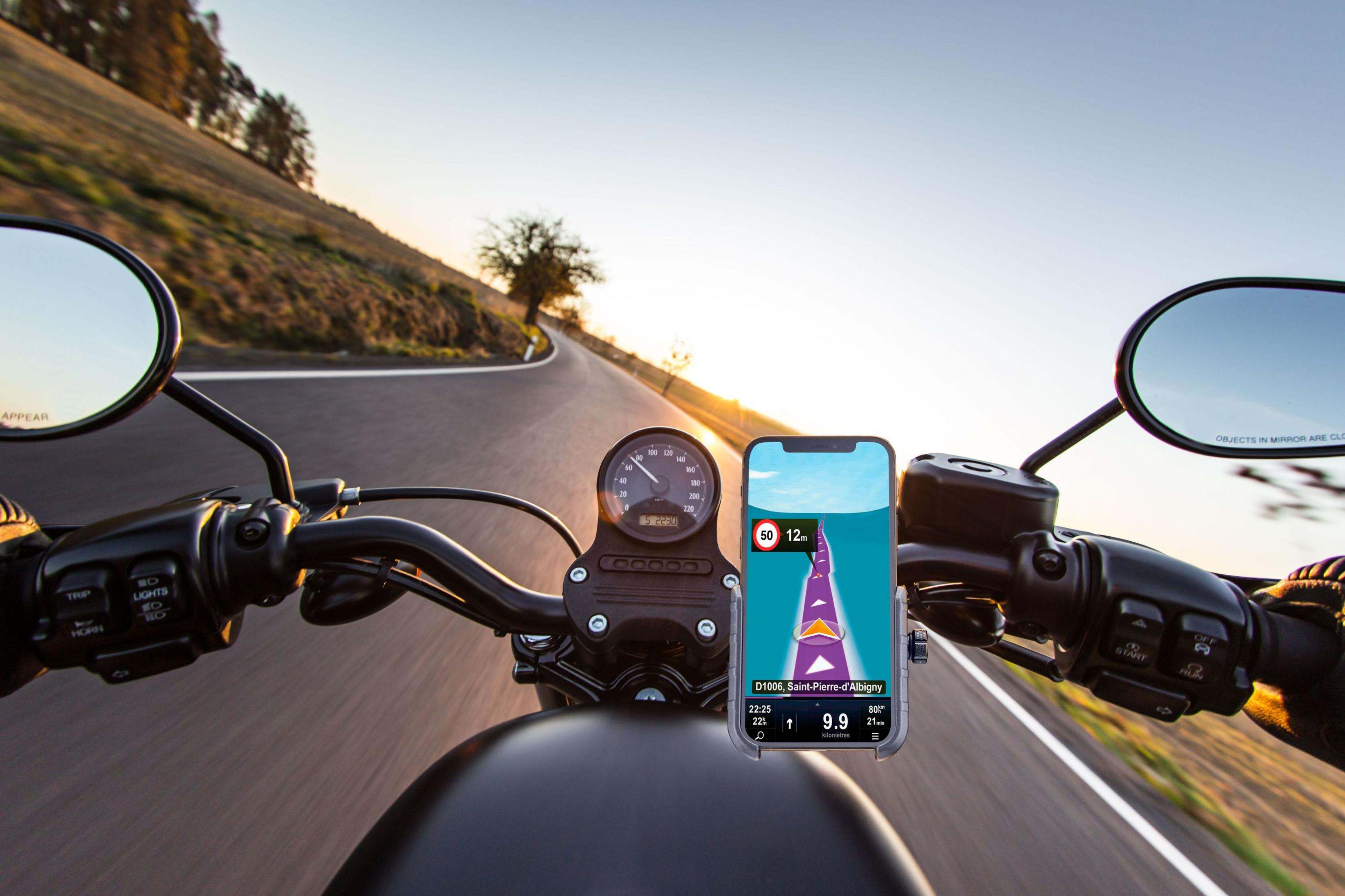 Giro in moto al tramonto con app di navigazione sul telefono.