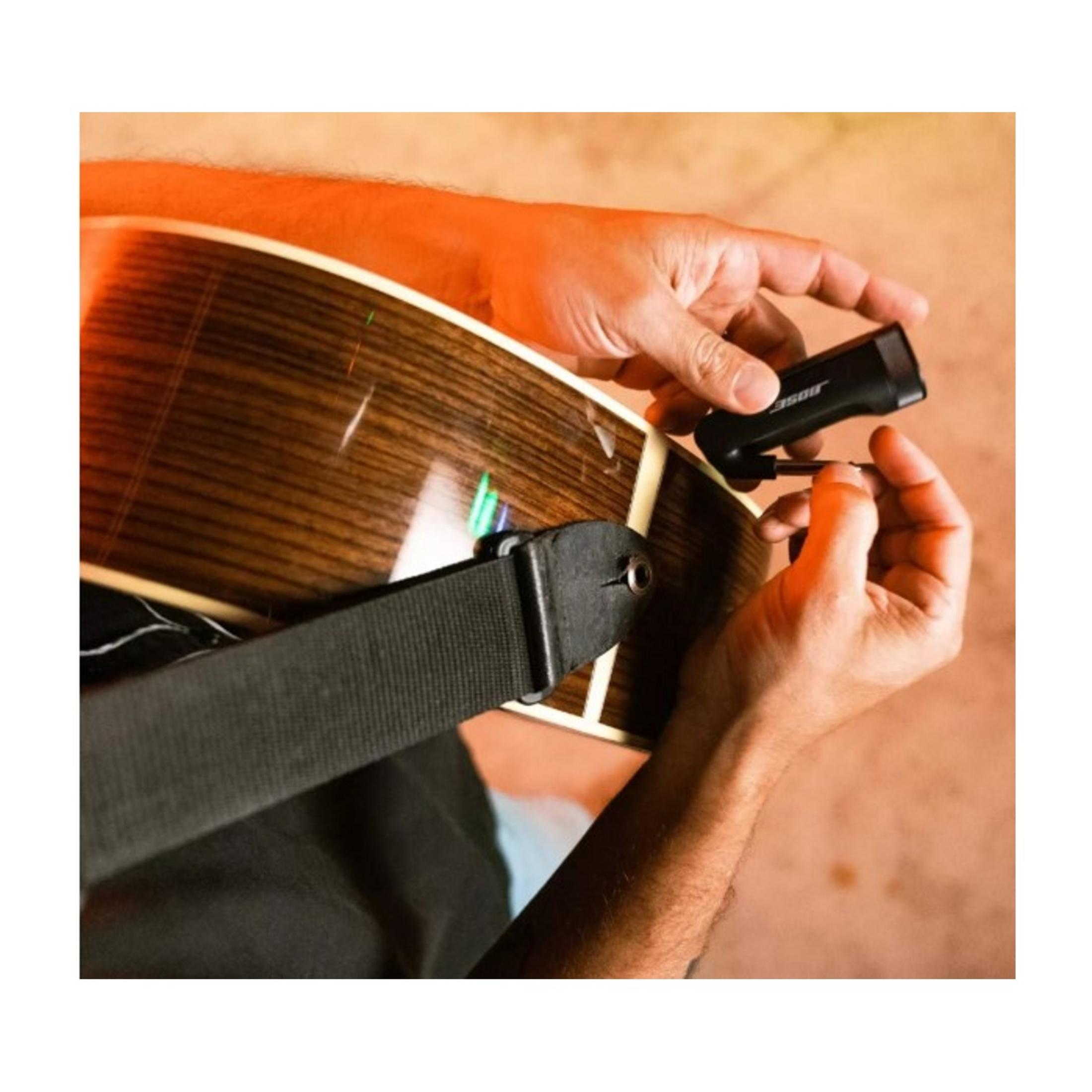 Mani che riparano una chitarra con uno strumento.