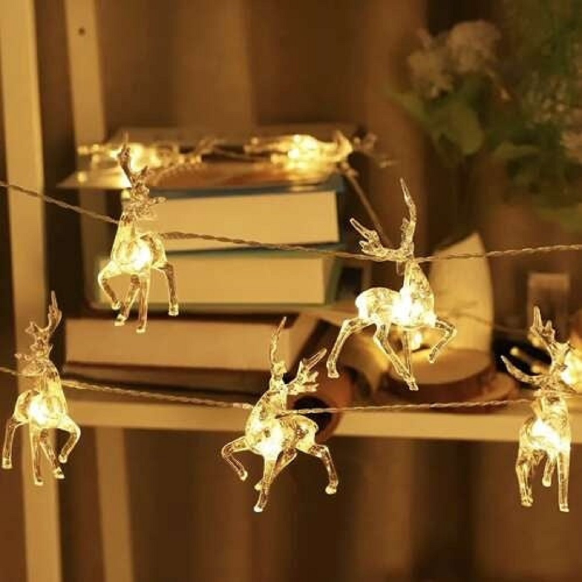 Cadena de luces con amuletos de reno transparentes en una estantería.