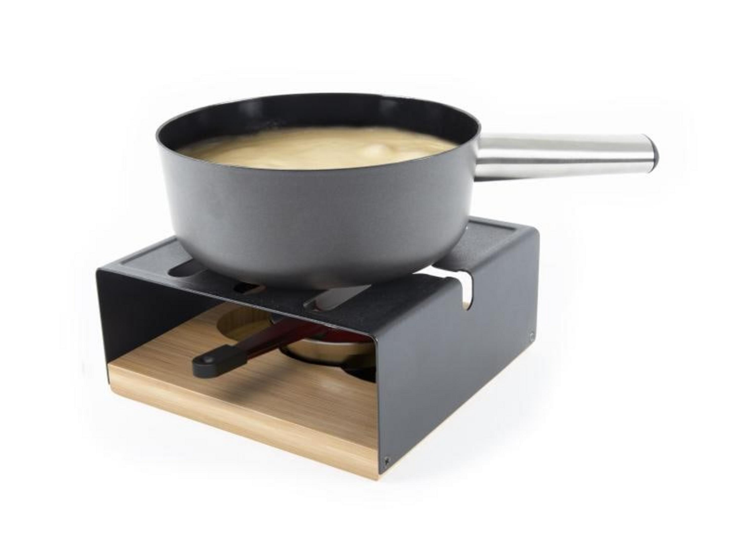 Una pentola di salsa gialla su un supporto nero con base in legno.