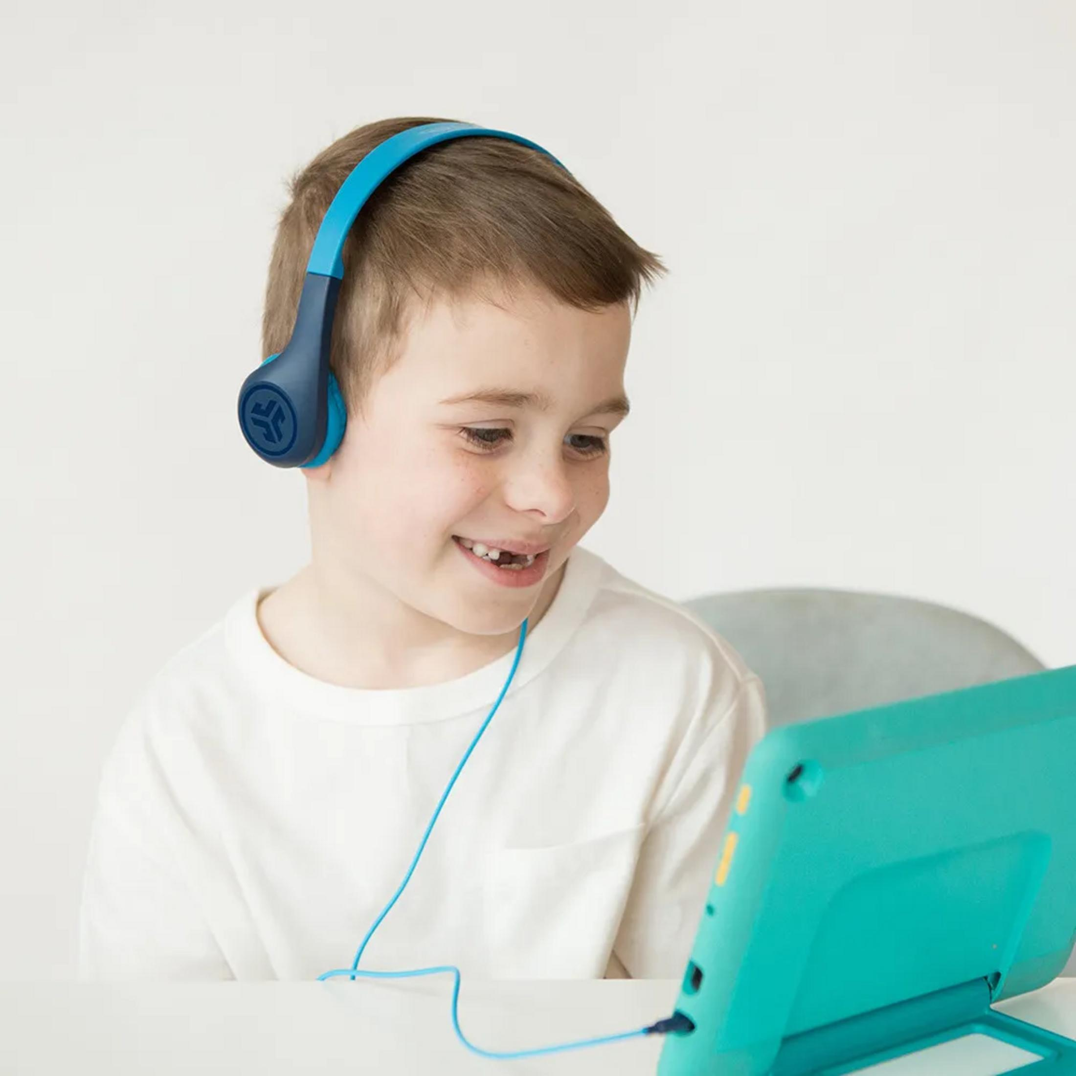 Chłopiec w słuchawkach patrzy na tablet.