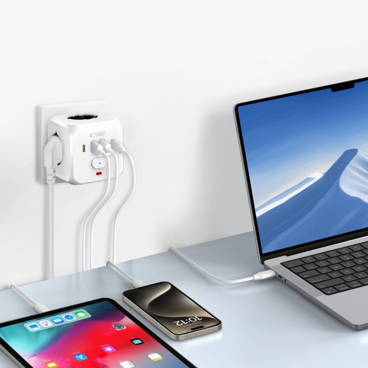 Ein weißer Reiseadapter lädt Laptop, Tablet und Smartphone. Modernes Setup.