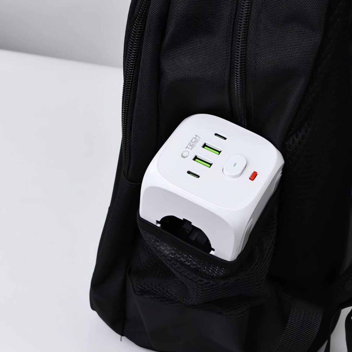 Ein weißer Reiseadapter mit USB-Anschlüssen steckt in einer schwarzen Tasche.