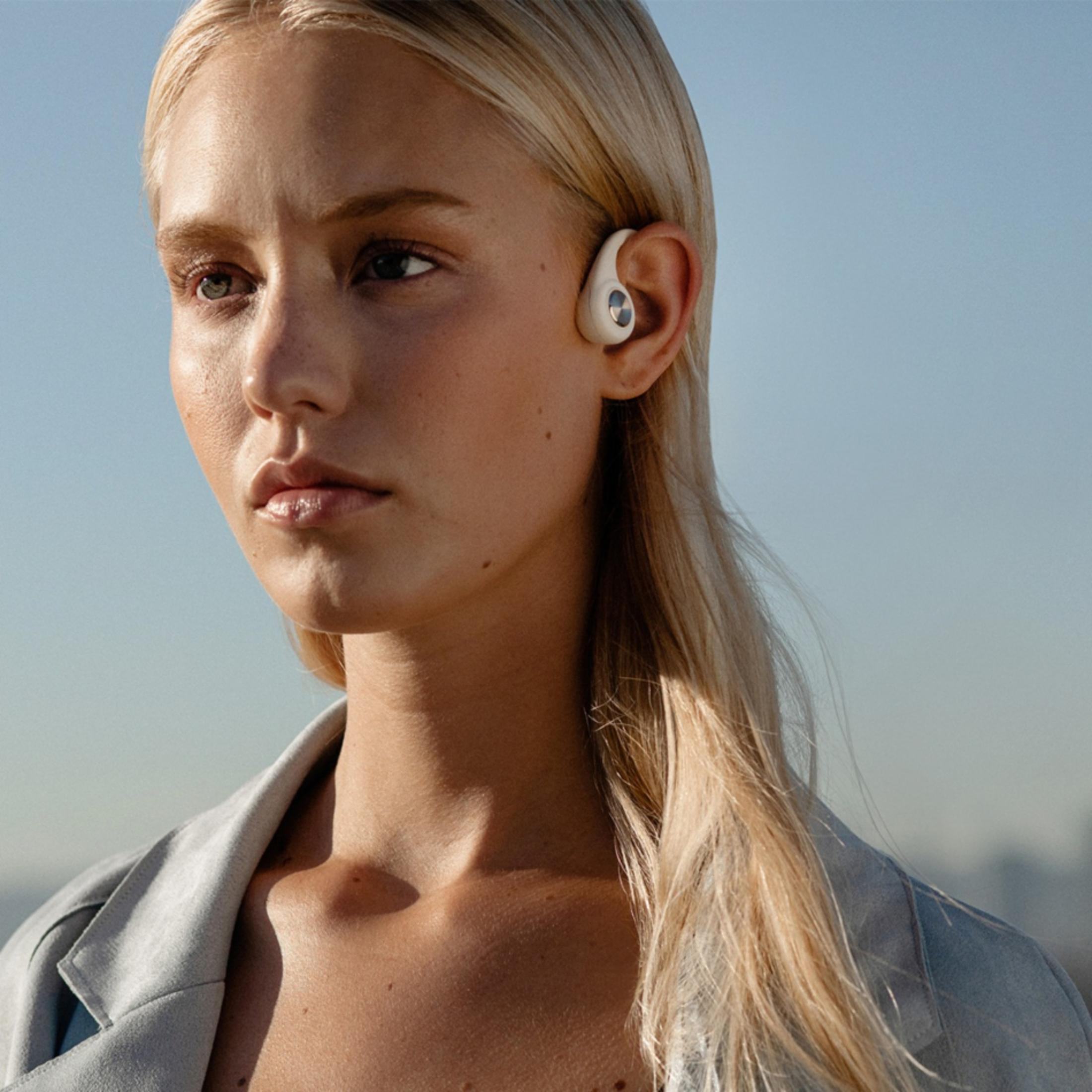 Una donna con i capelli biondi indossa un blazer blu e un auricolare bianco.