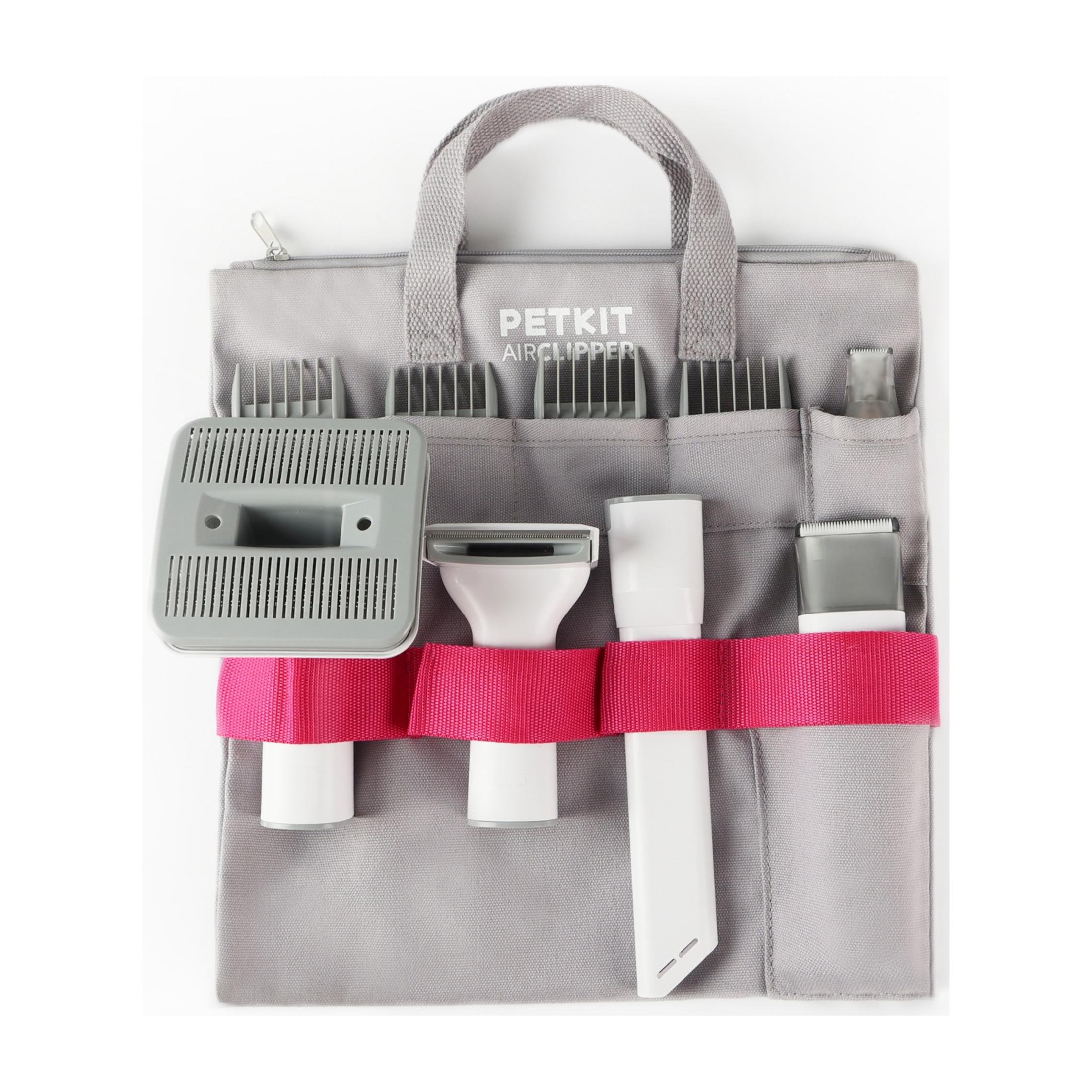 Graue Tasche mit Haarschneidegeräten und Aufsätzen, gehalten von pinkem Band.