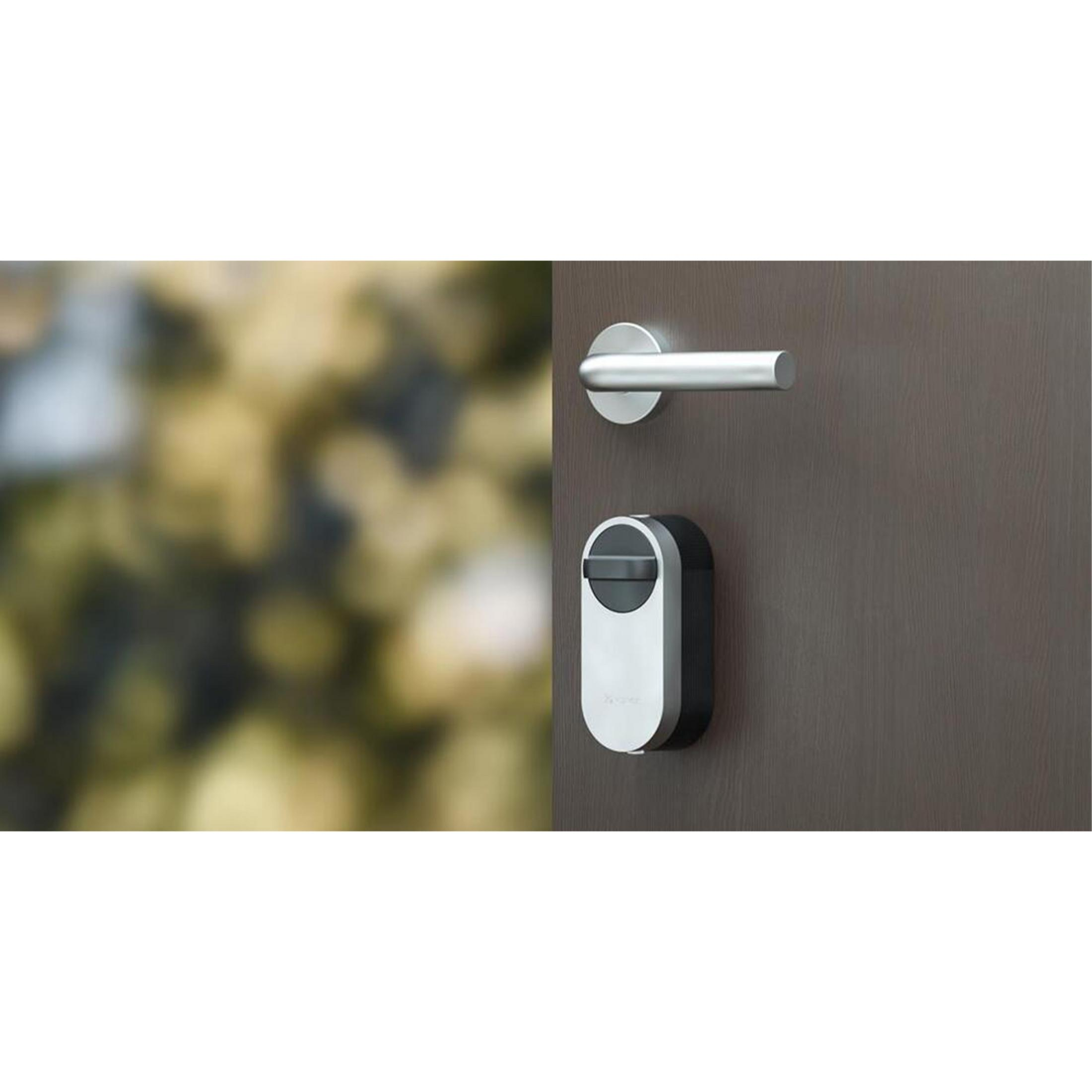 Un pomo de puerta plateado y un moderno mecanismo de cerradura negro/plateado en una puerta de madera marrón.